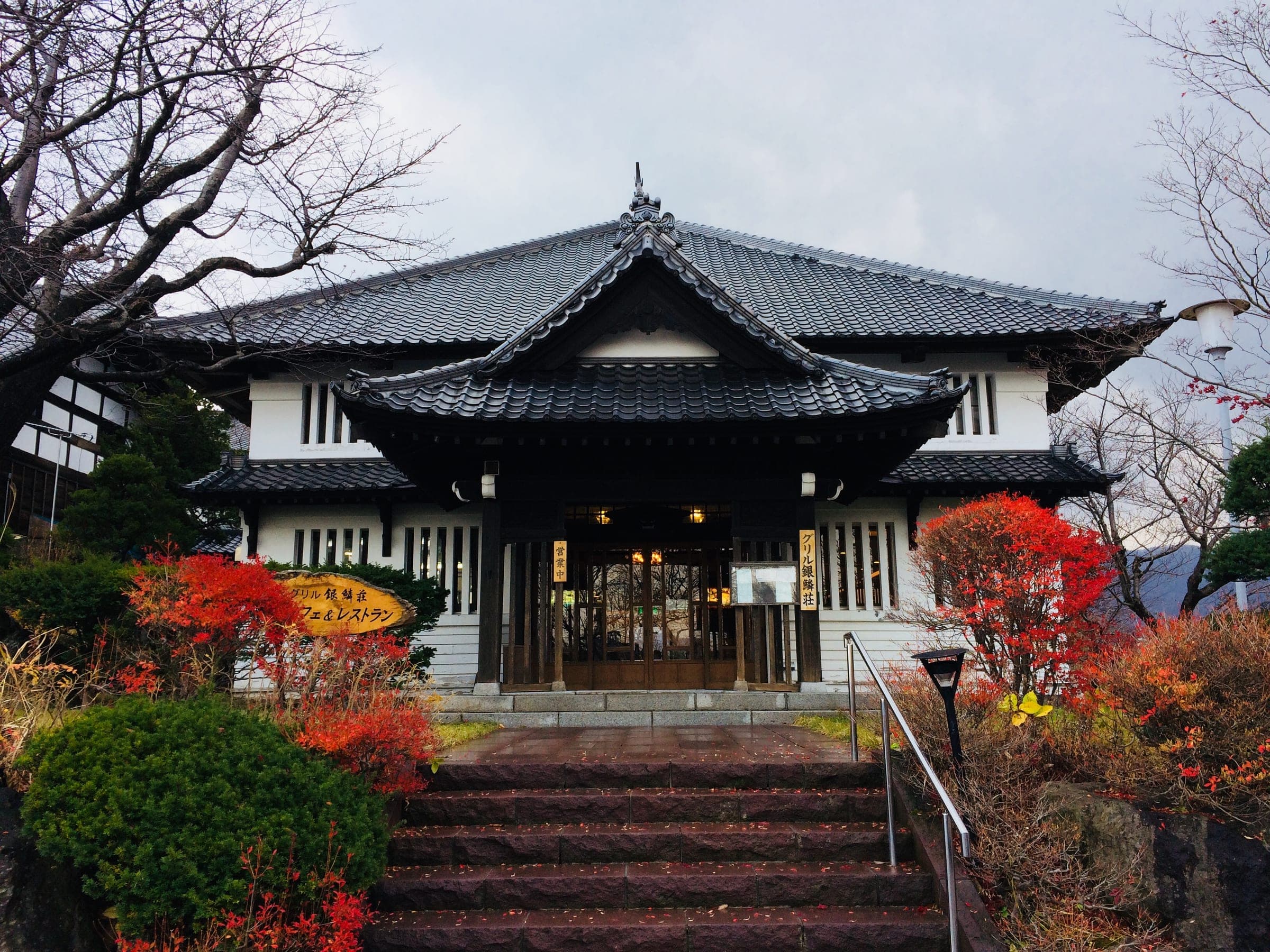 The gabled entrance hall of Ginrinsou framed by red autumn maples