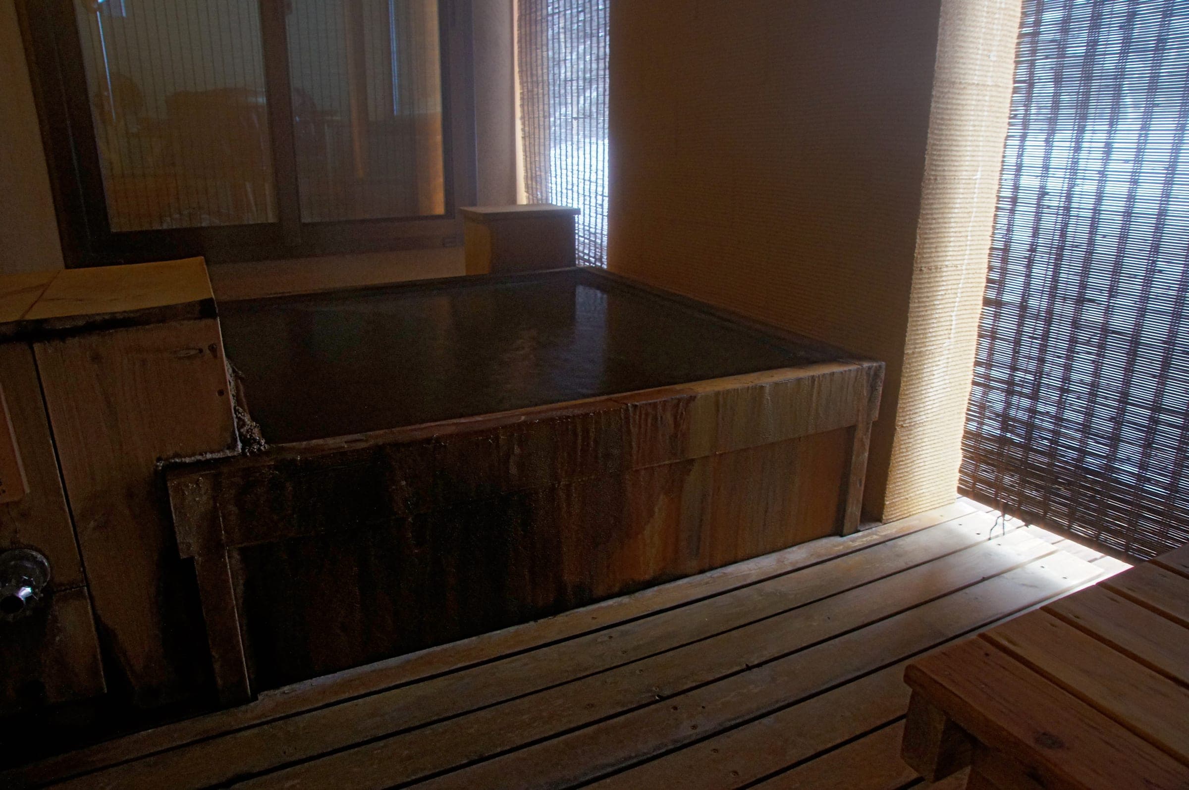 A wooden private bath at Morino Ryotei Biei lit through bamboo blinds