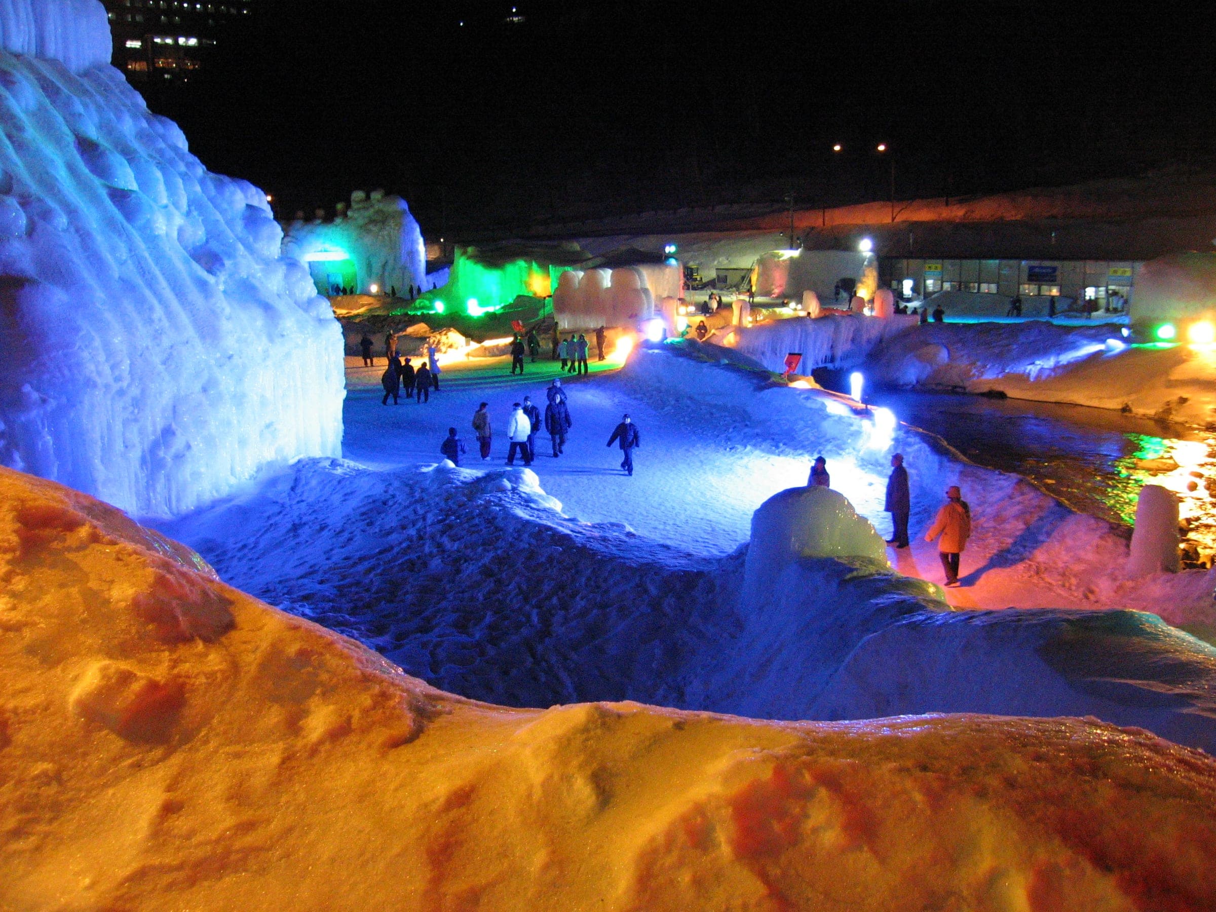 Lit ice walls and towers fill the Sounkyo Ice Fall Festival grounds in Sounkyo Onsen at night
