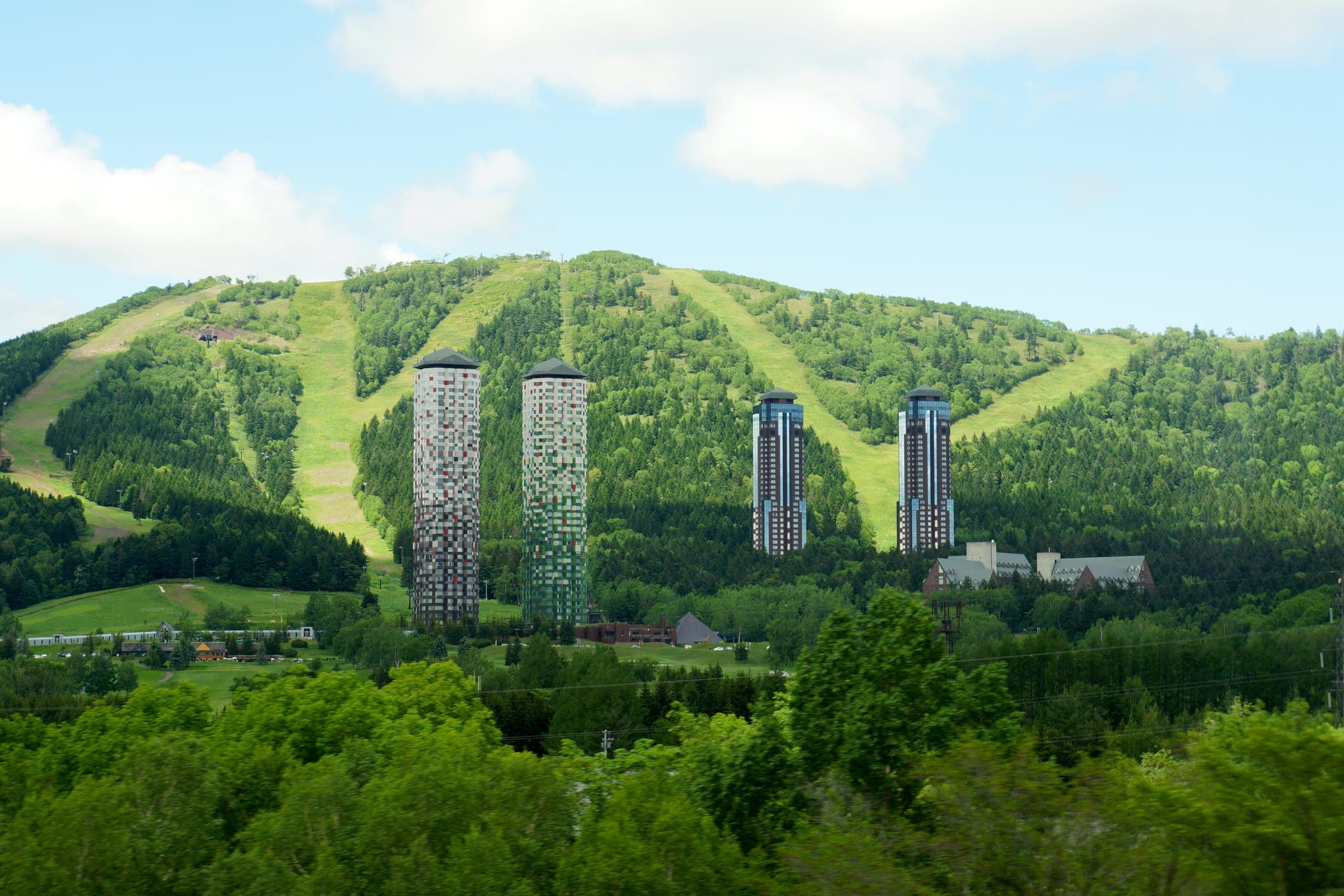 The Tower and its neighbouring hotel towers below green Tomamu ski runs in summer