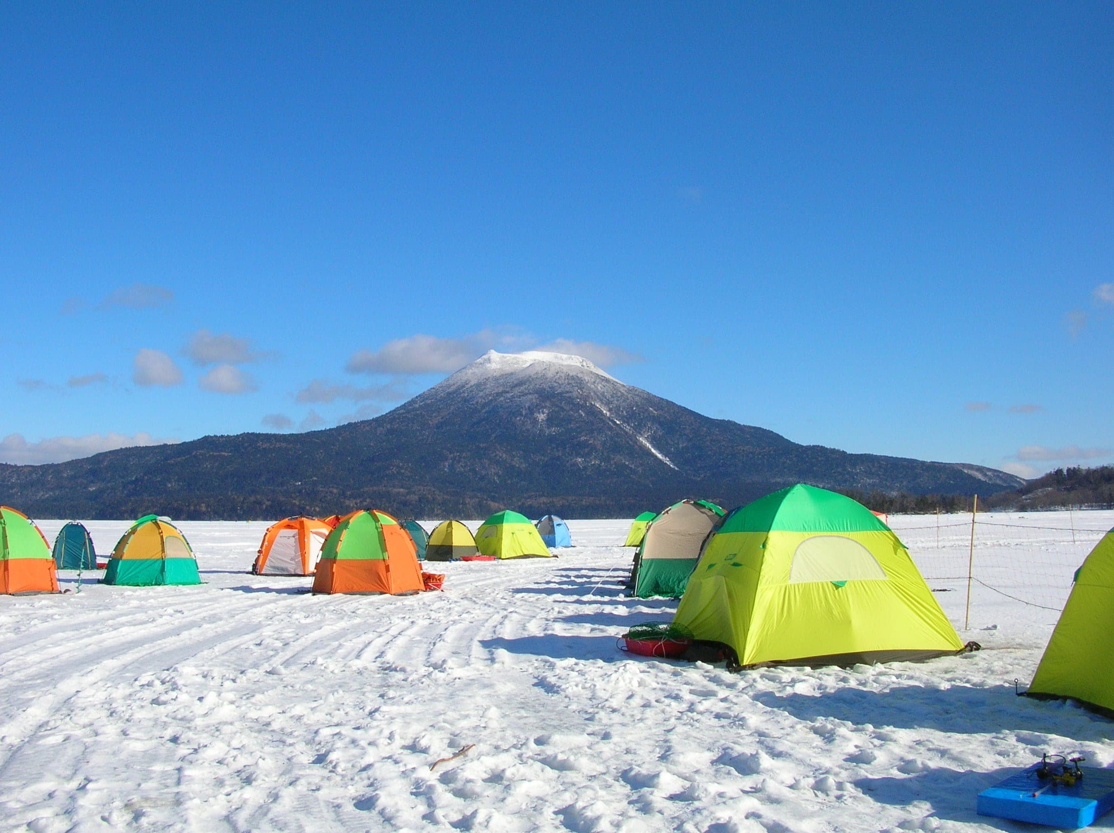 Ice fishing tents dot frozen Lake Akan below Mt. Oakan