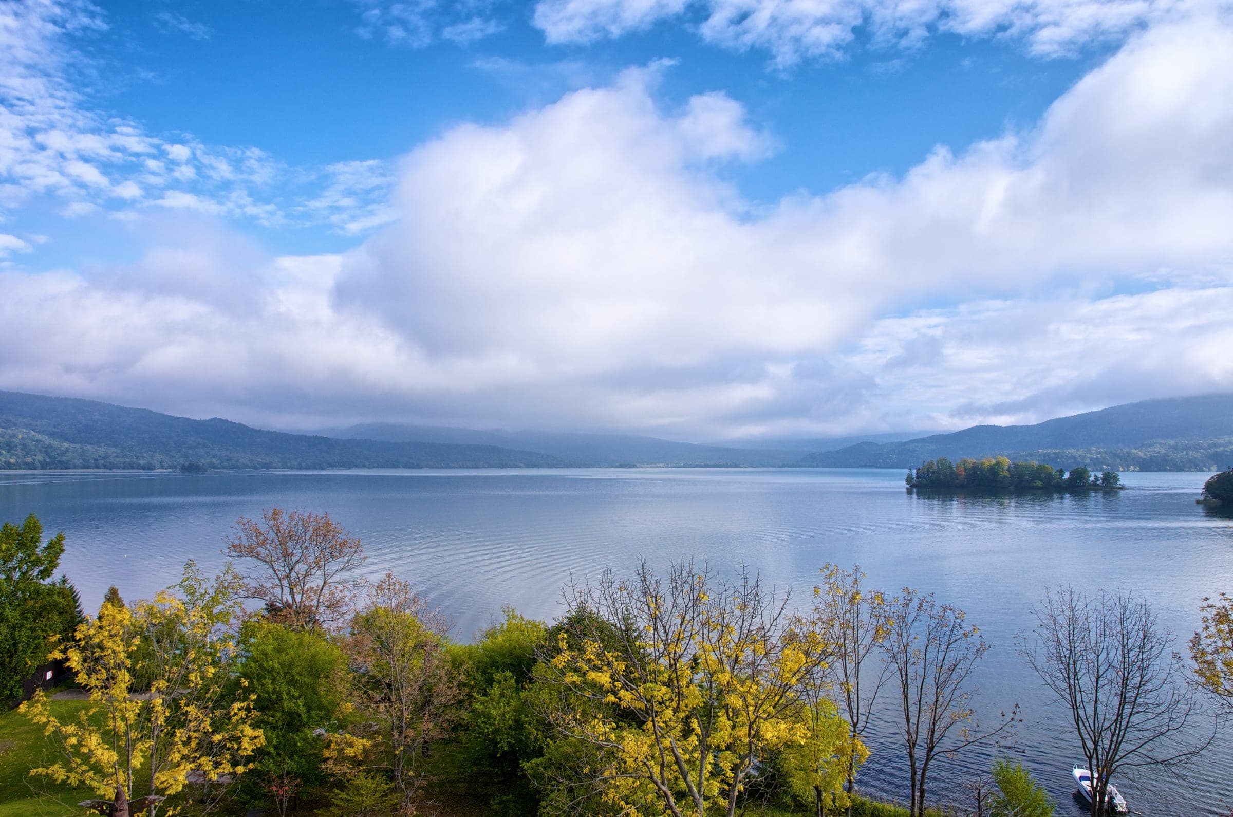 Lake Akan seen through autumn leaves with islands under a cloudy sky