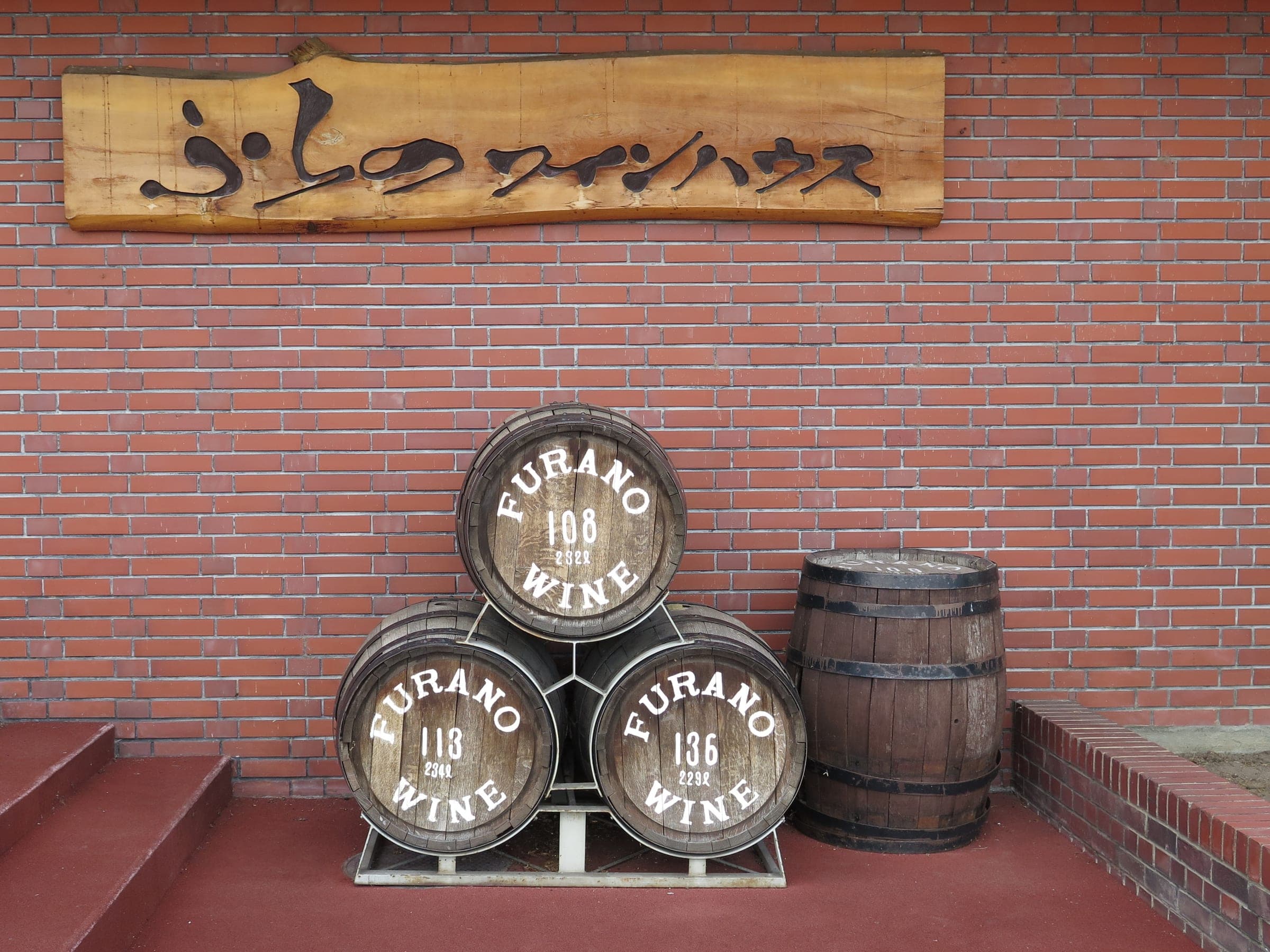 Furano Wine barrels stacked under the carved sign of the Furano Wine House