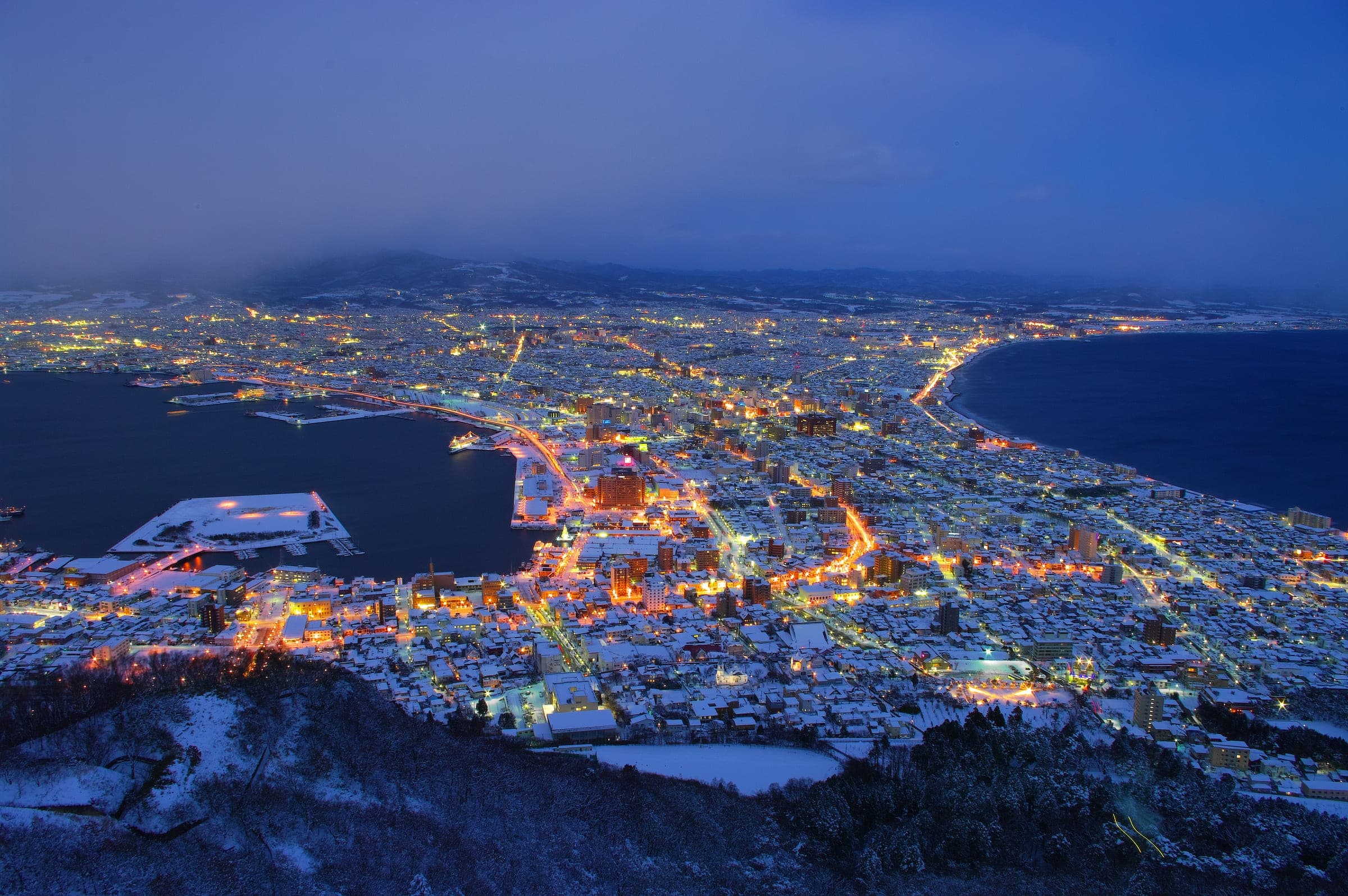 The lights of Hakodate fill the isthmus below Mt. Hakodate on a snowy evening