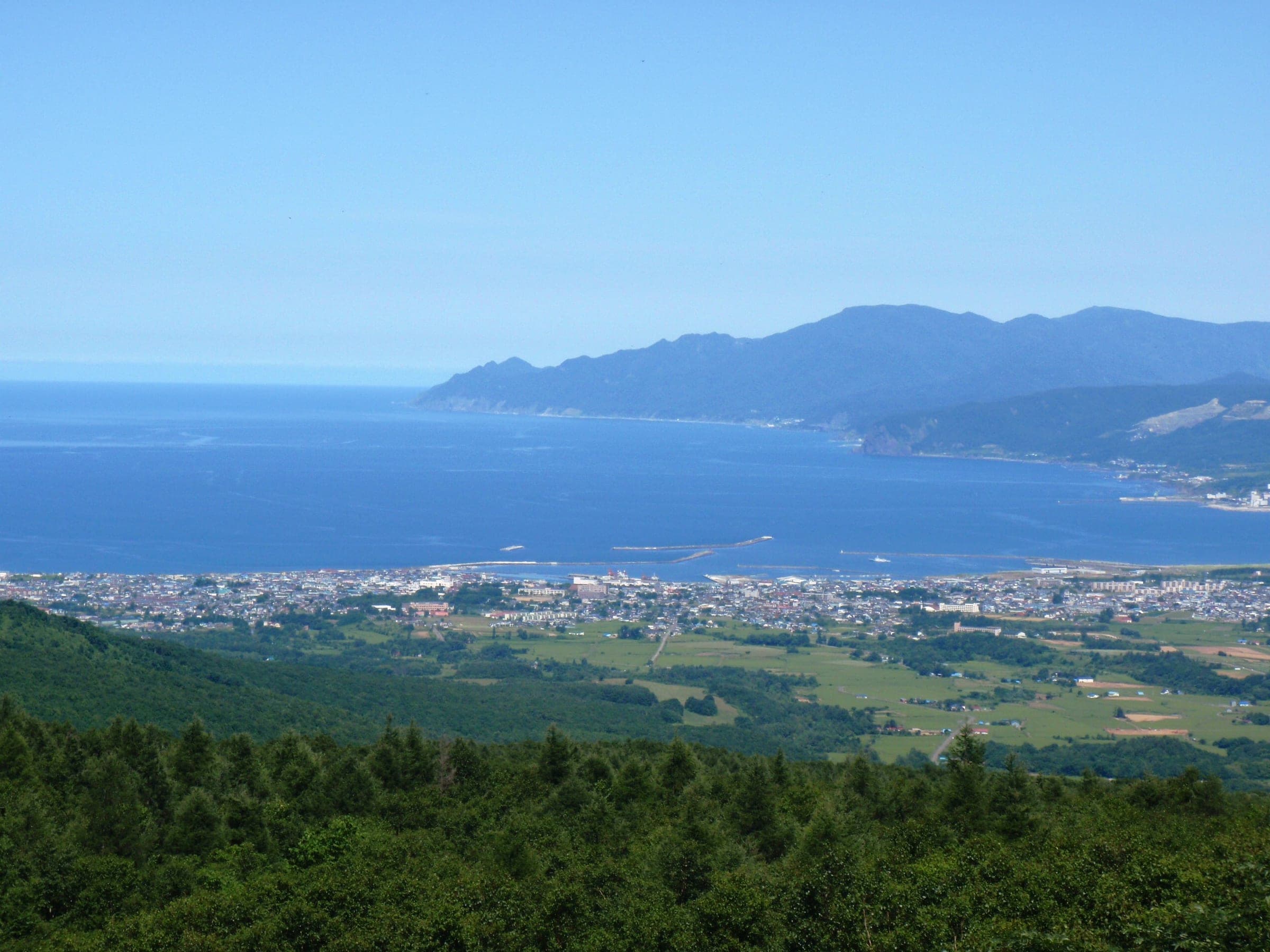 Iwanai's town spreads along a blue bay below the Niseko Panorama Line in summer