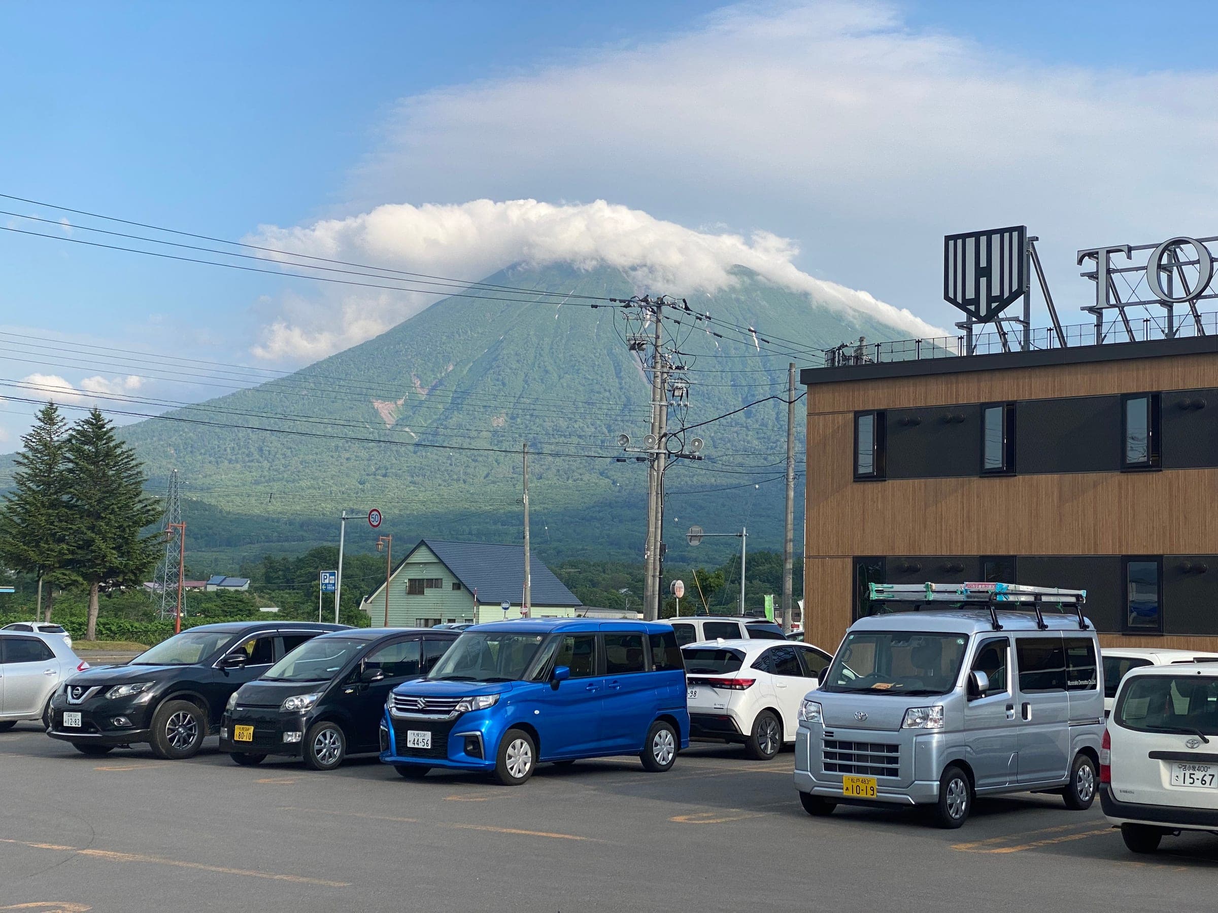 A cap of cloud sits on Mount Yotei above a Kutchan hotel and its car park
