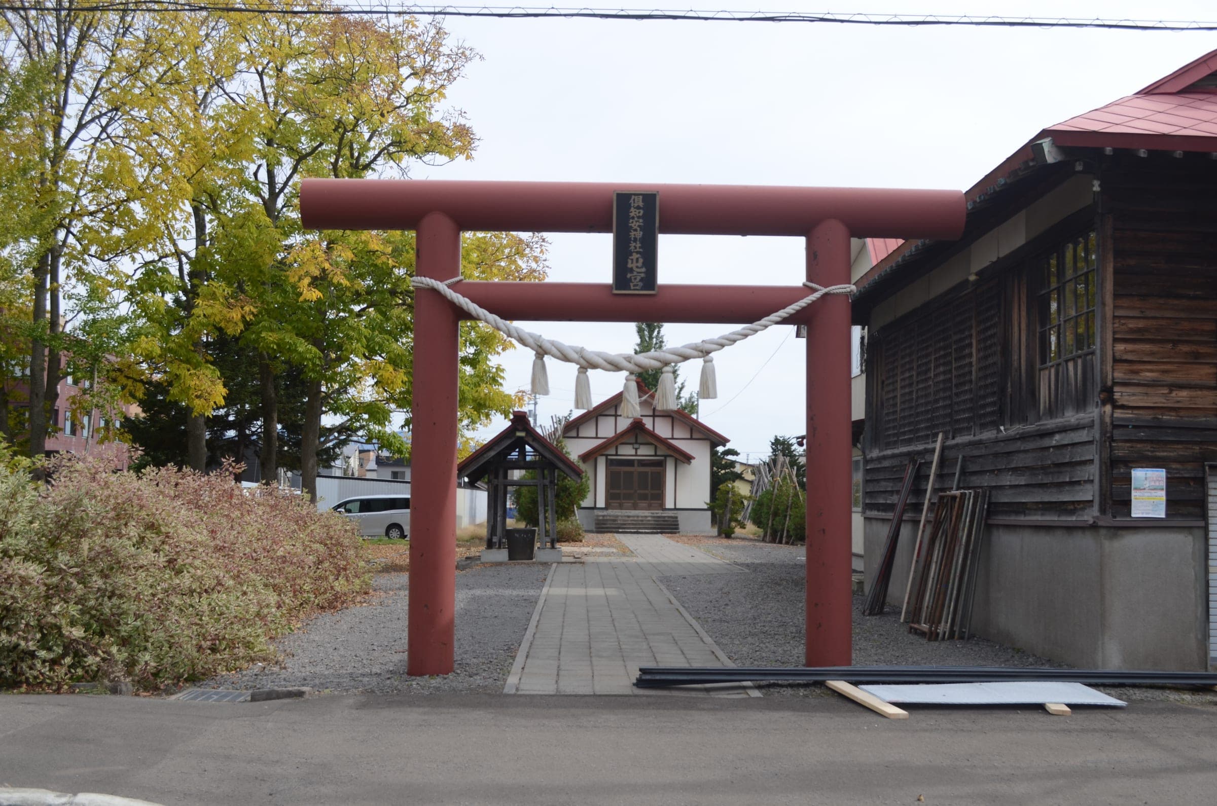 A red torii stands at the entrance to Kutchan Shrine among autumn trees