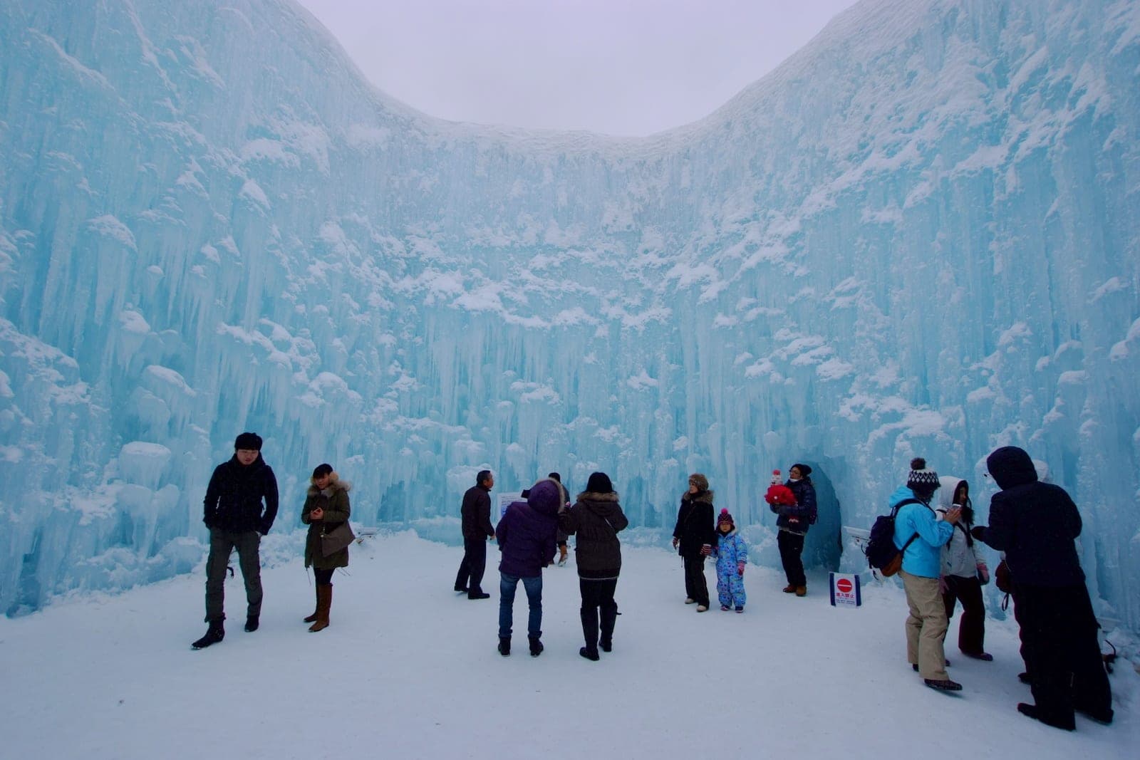 Visitors stand among towering blue ice walls at the Lake Shikotsu Ice Festival