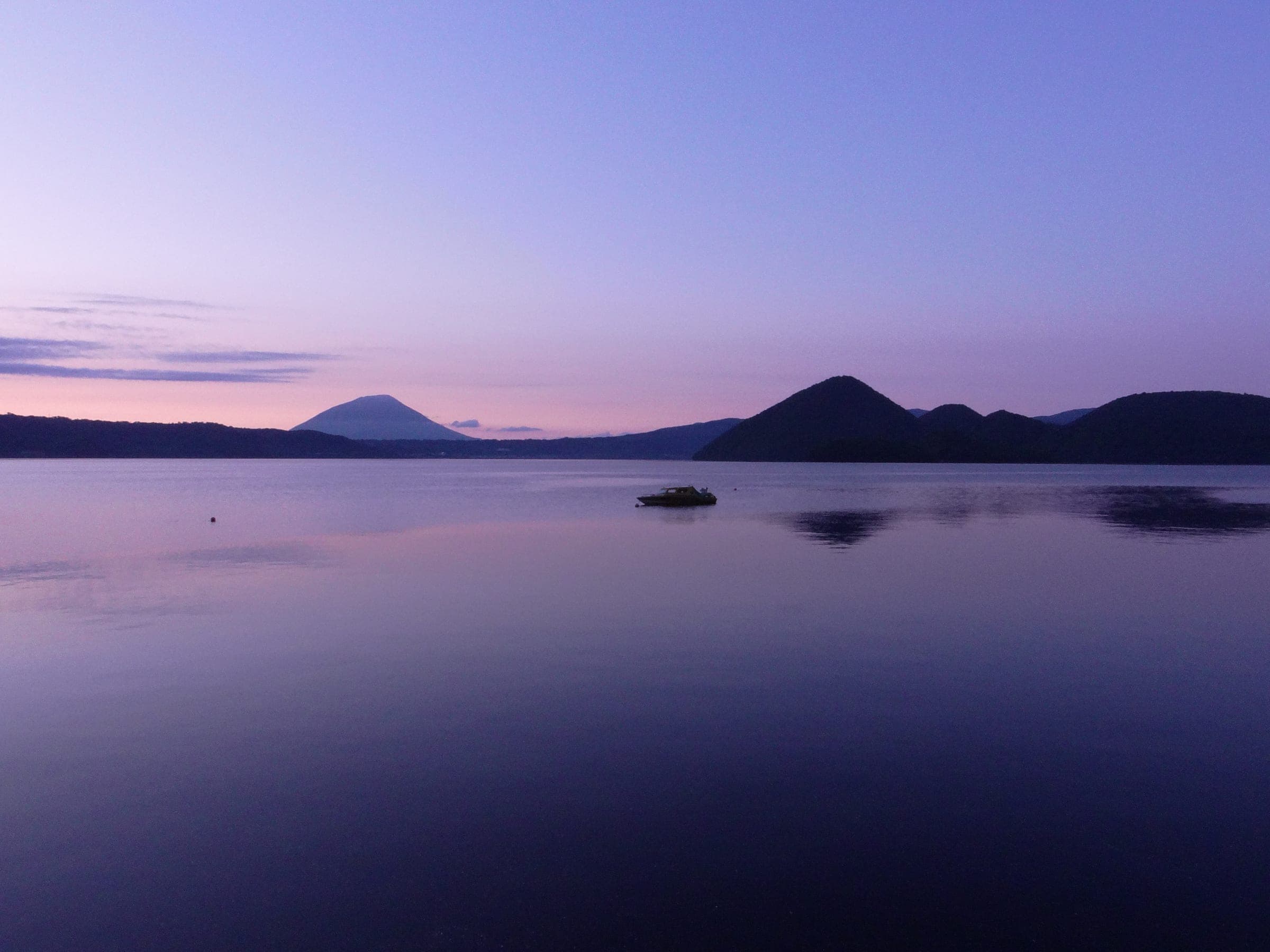Lake Toya at dusk under a violet sky with Mount Yotei in the distance