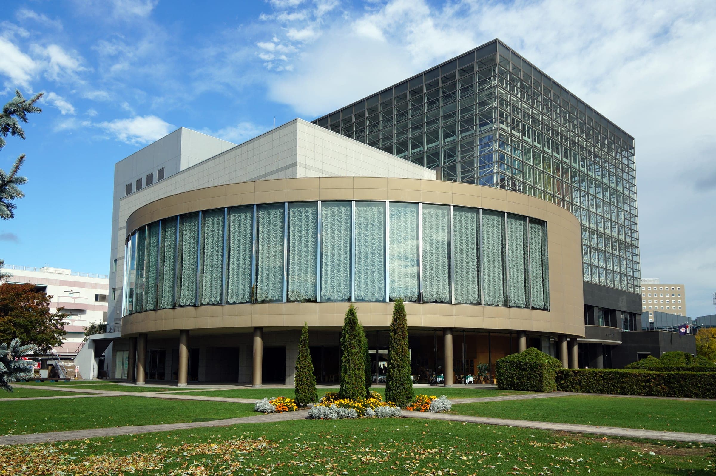 Tokachi Plaza's glass tower rises above a round hall and flower beds in Obihiro