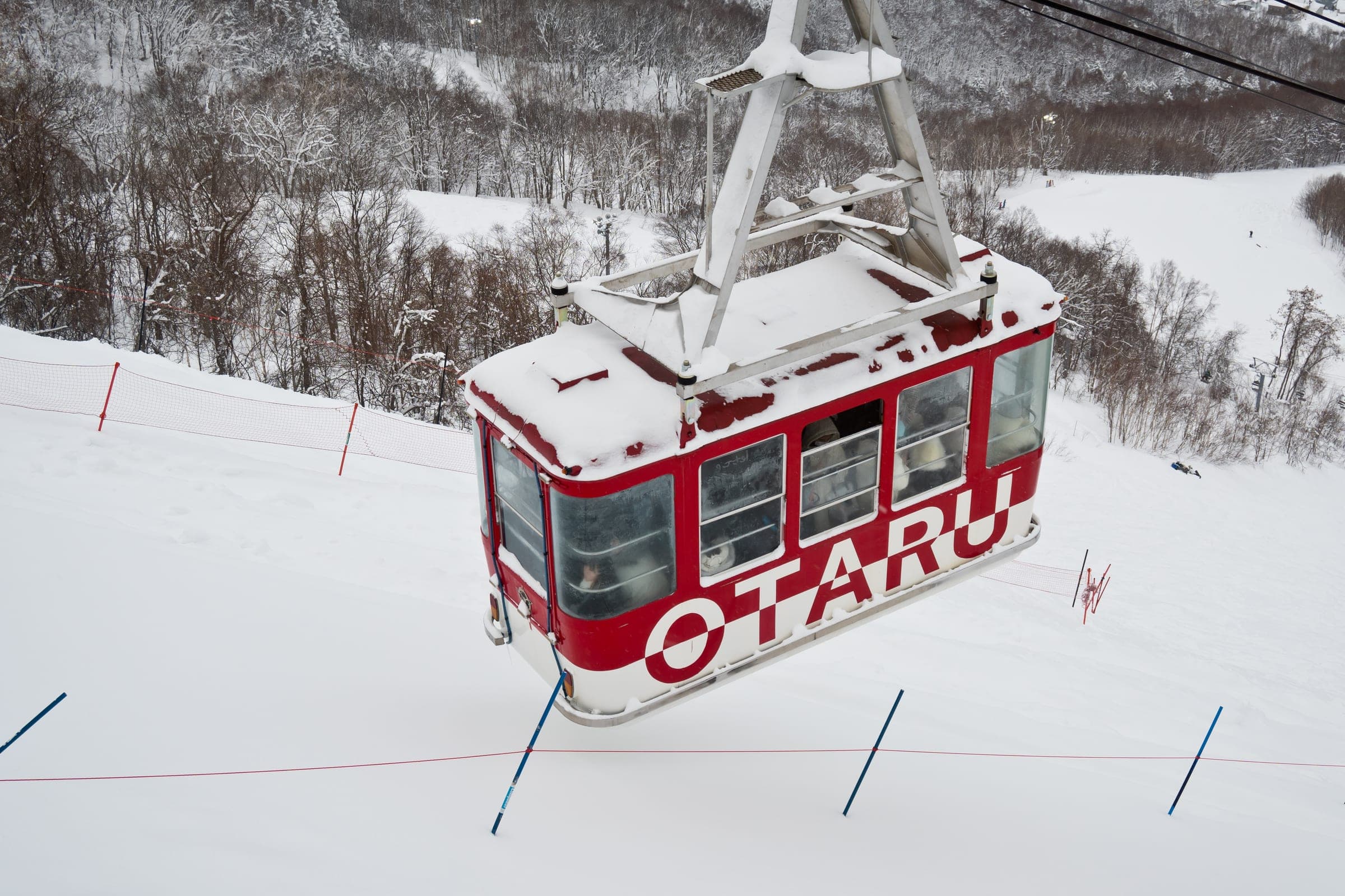 The red Otaru cabin of the Tenguyama Ropeway passes over snowy slopes