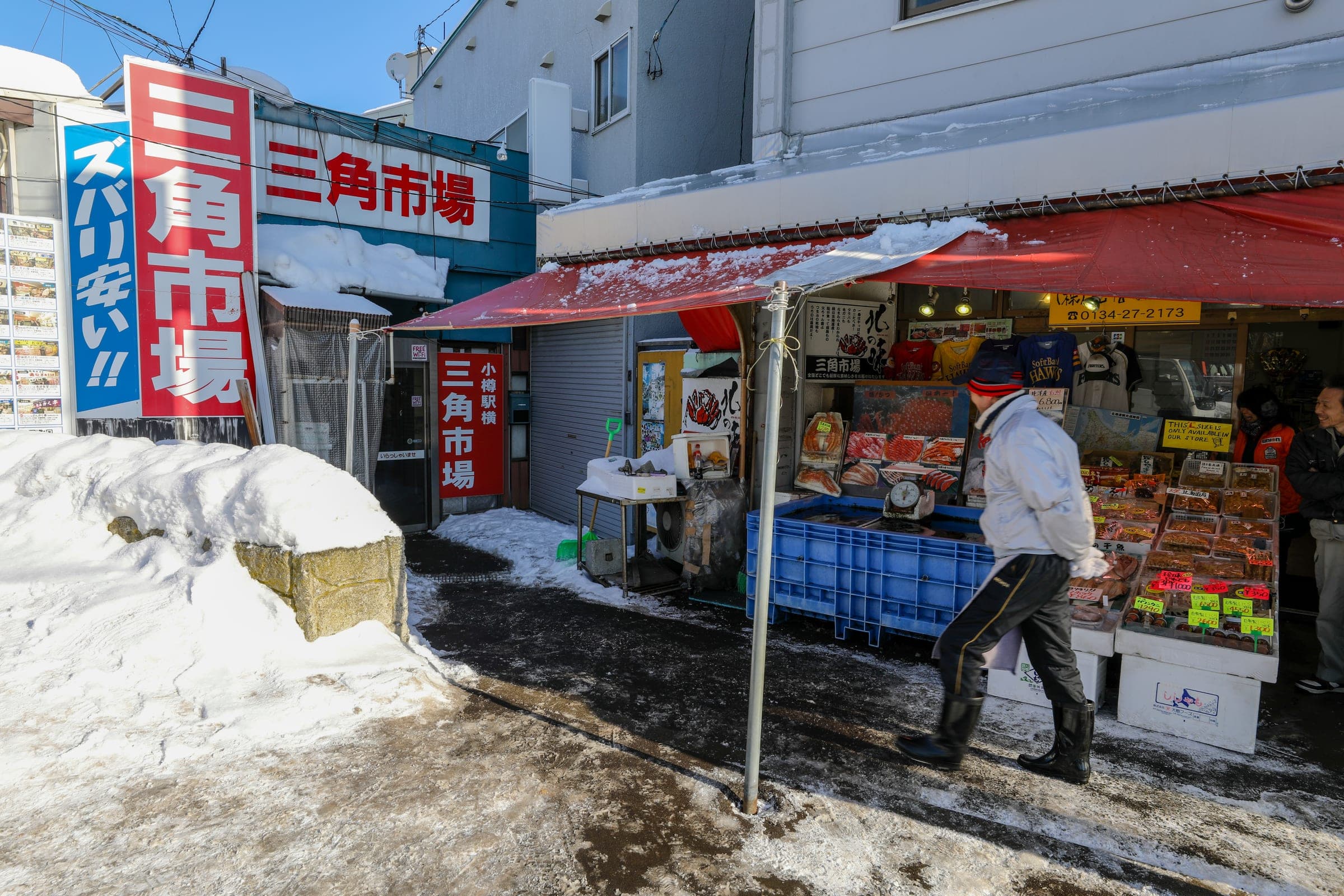 The entrance of Otaru Sankaku Market with its red sign and snow piled outside