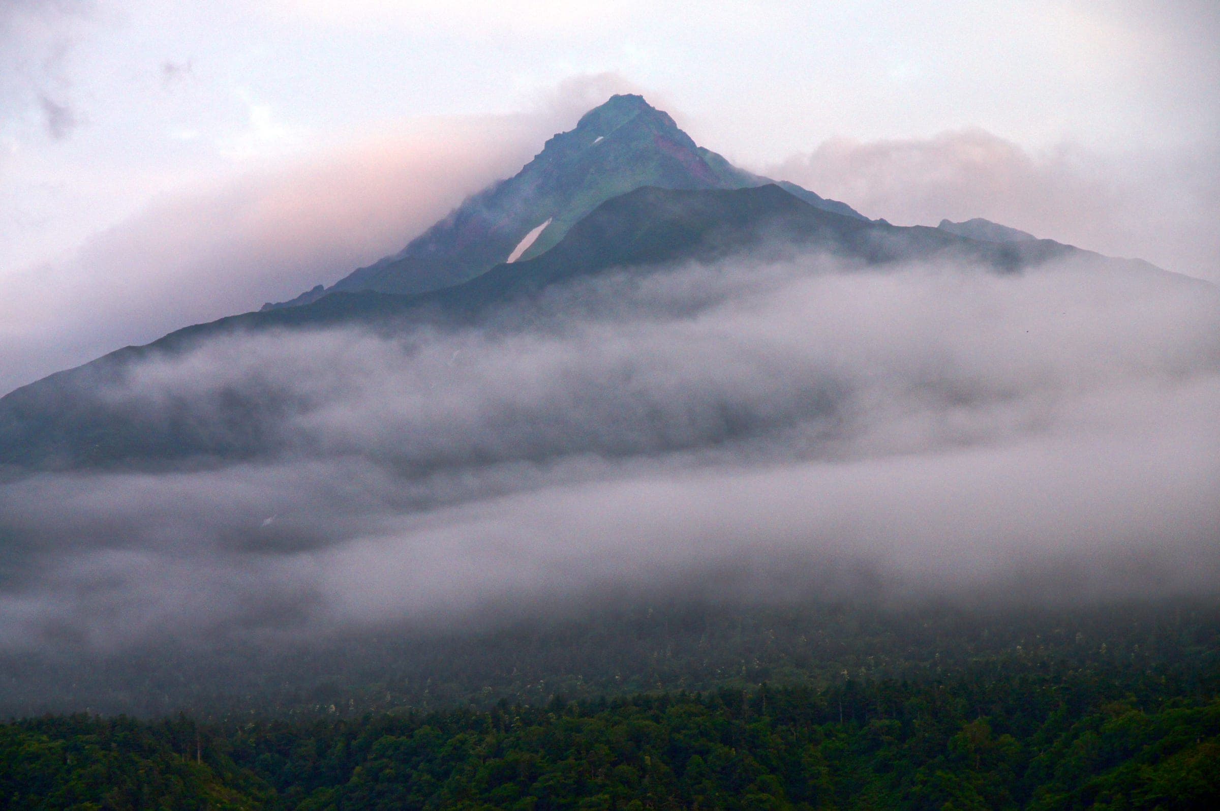 Cloud wraps the lower slopes of Mount Rishiri above the sea at Oshidomari