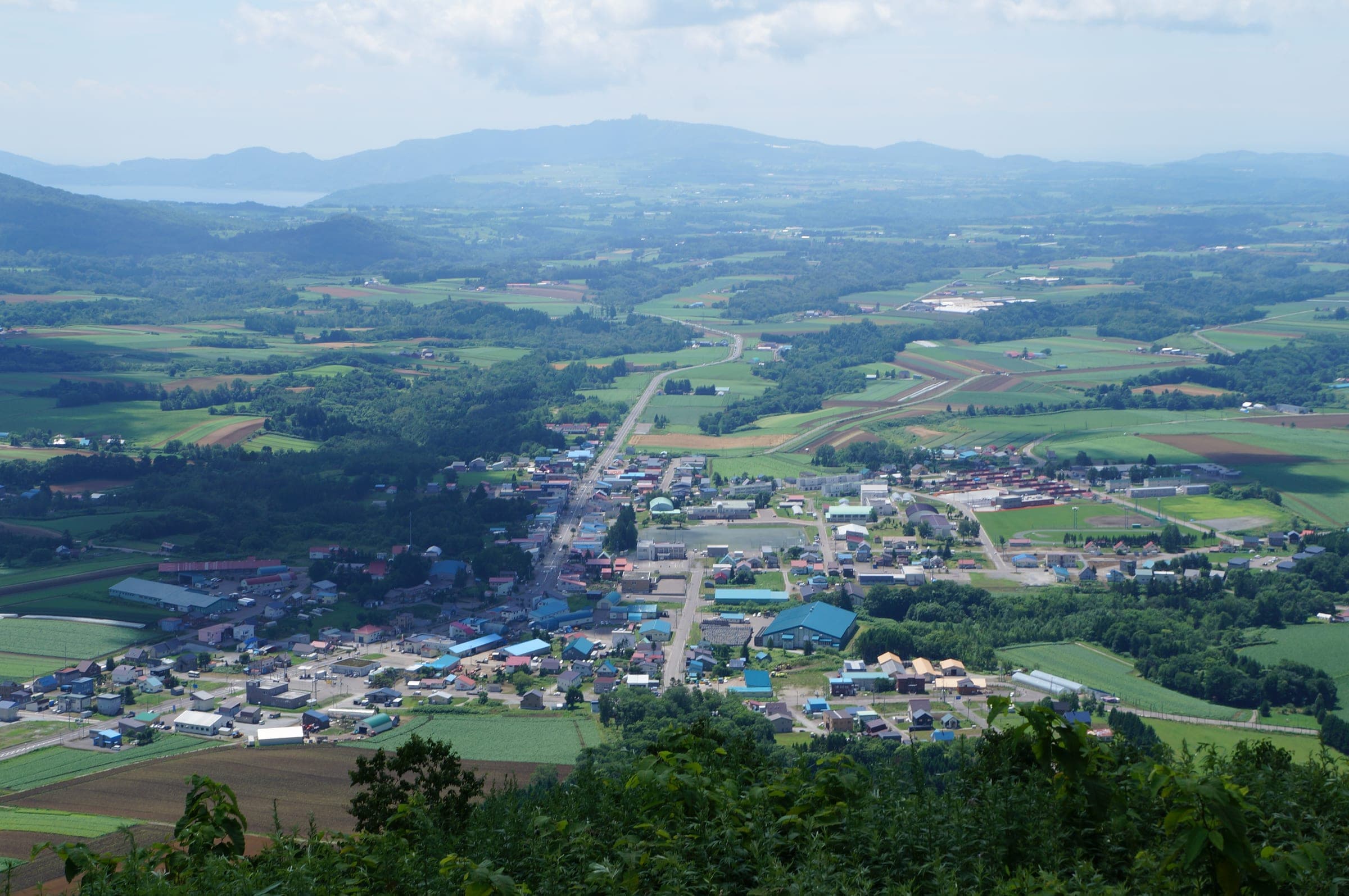 Rusutsu village spreads across green farmland seen from the hills above in summer