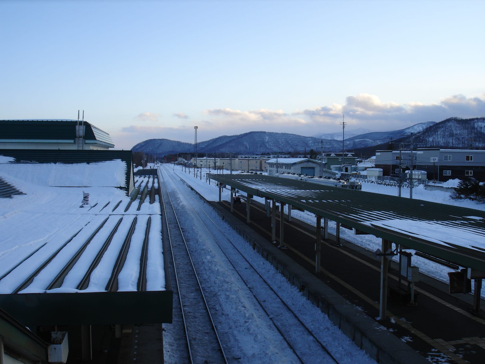Snow covers the platforms at Shintoku Station below the hills of Tokachi