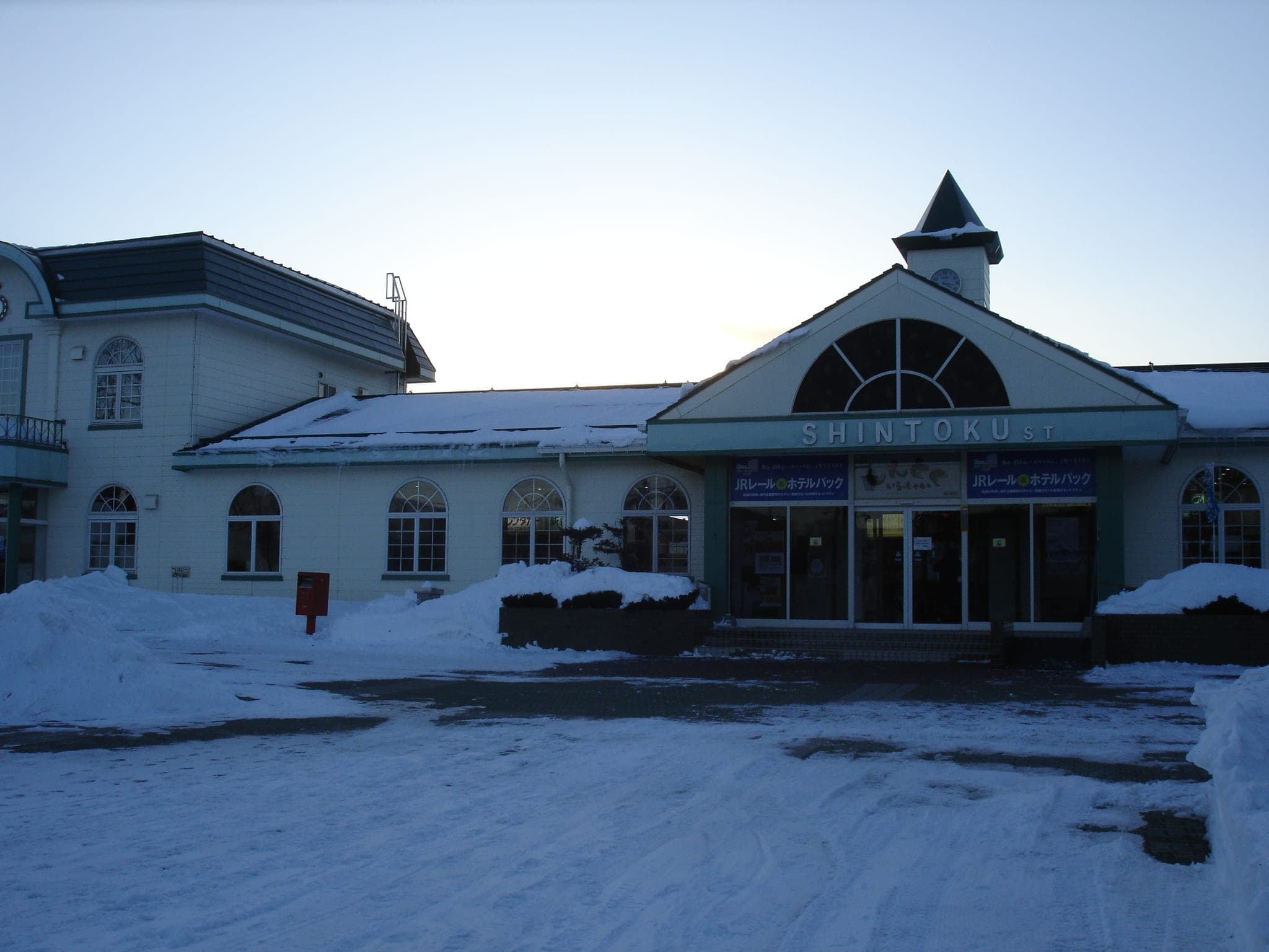 Snow lies in front of Shintoku Station and its arched window under a clear sky