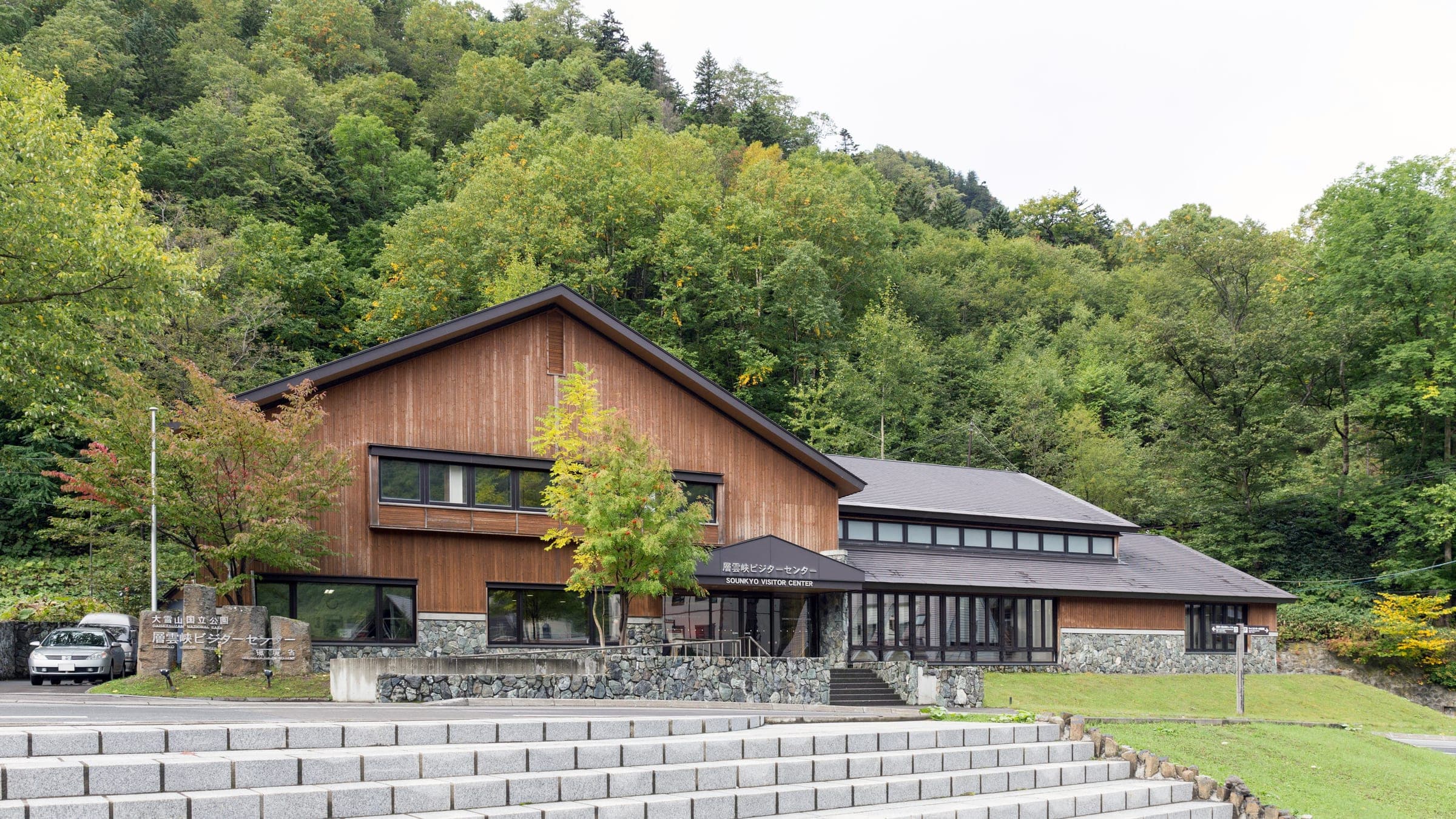 The wooden Sounkyo Visitor Center below forested slopes