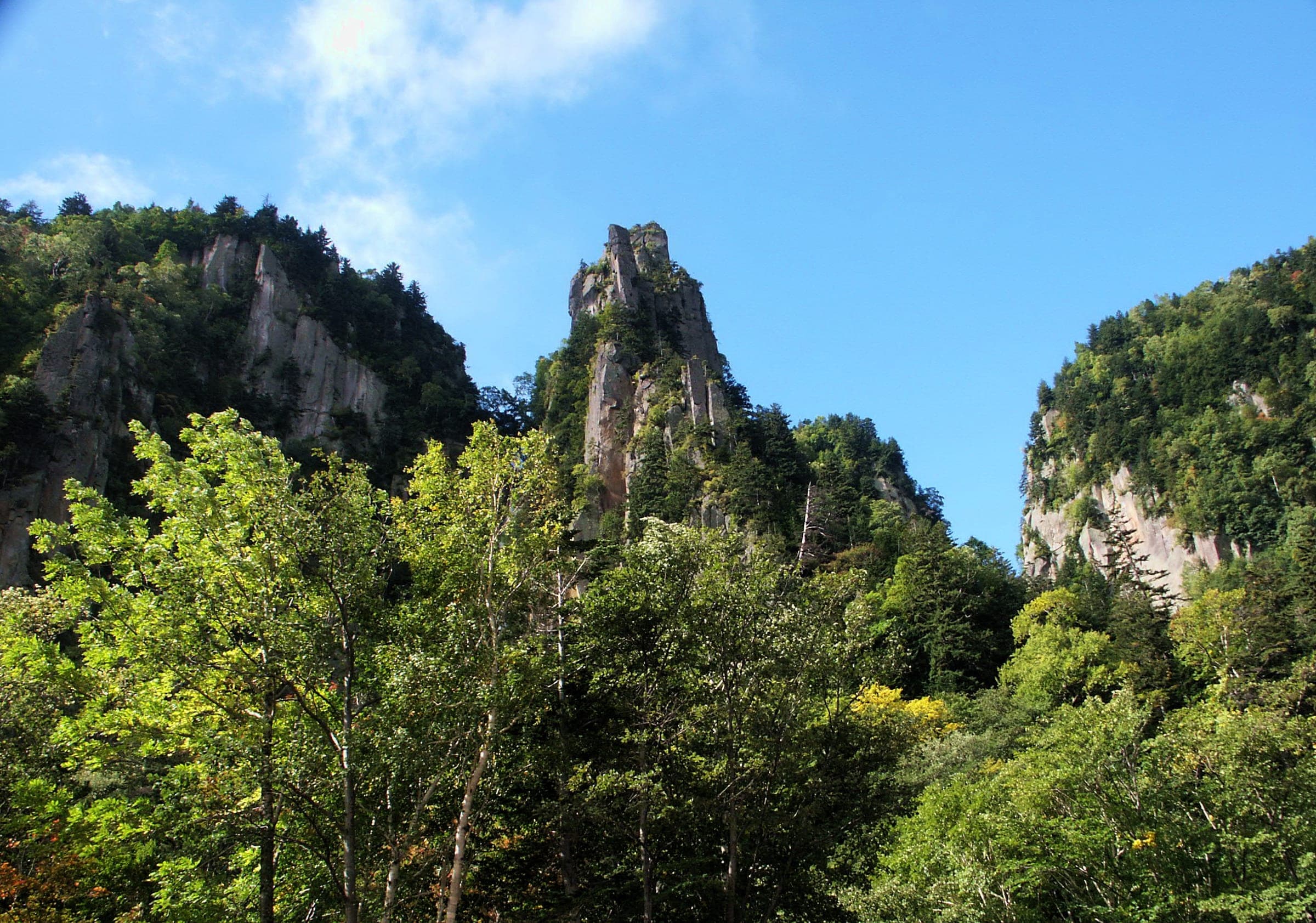 Rock pinnacles rise from green forest above the Sounkyo gorge in summer