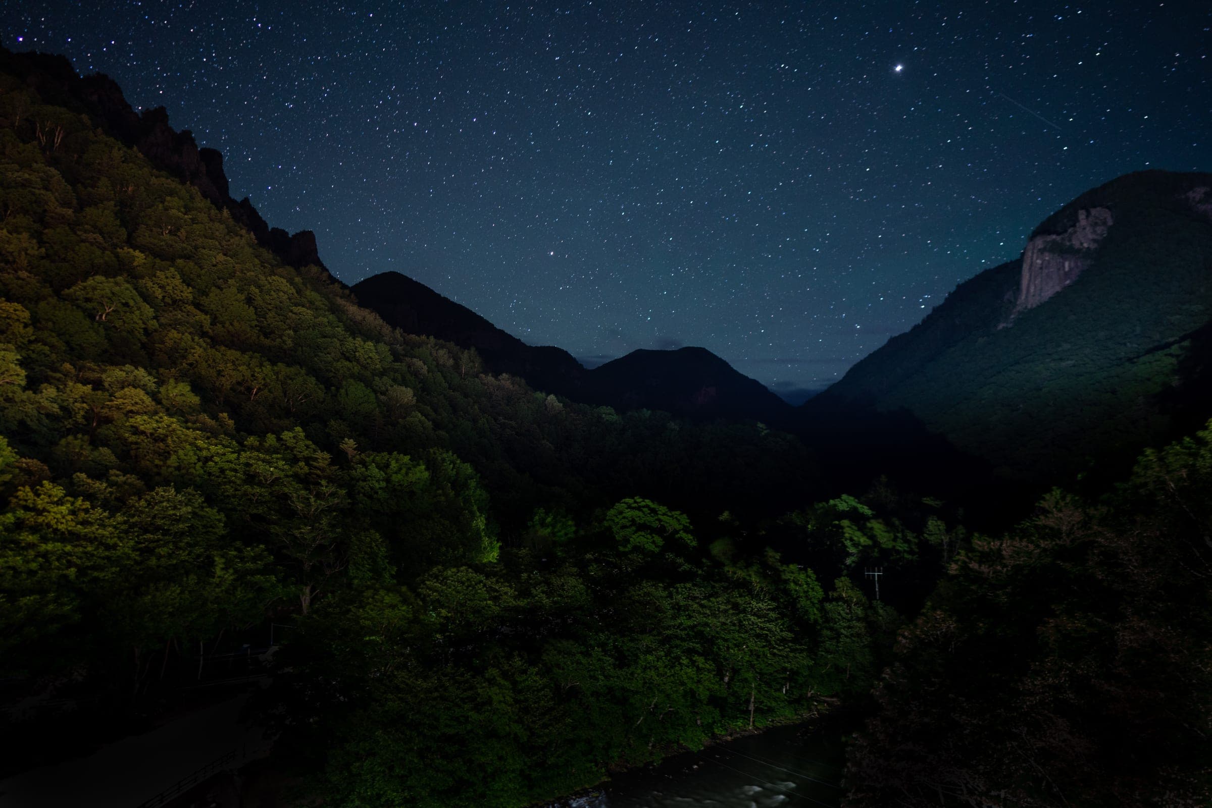 Stars fill the night sky above the dark walls of Sounkyo Canyon