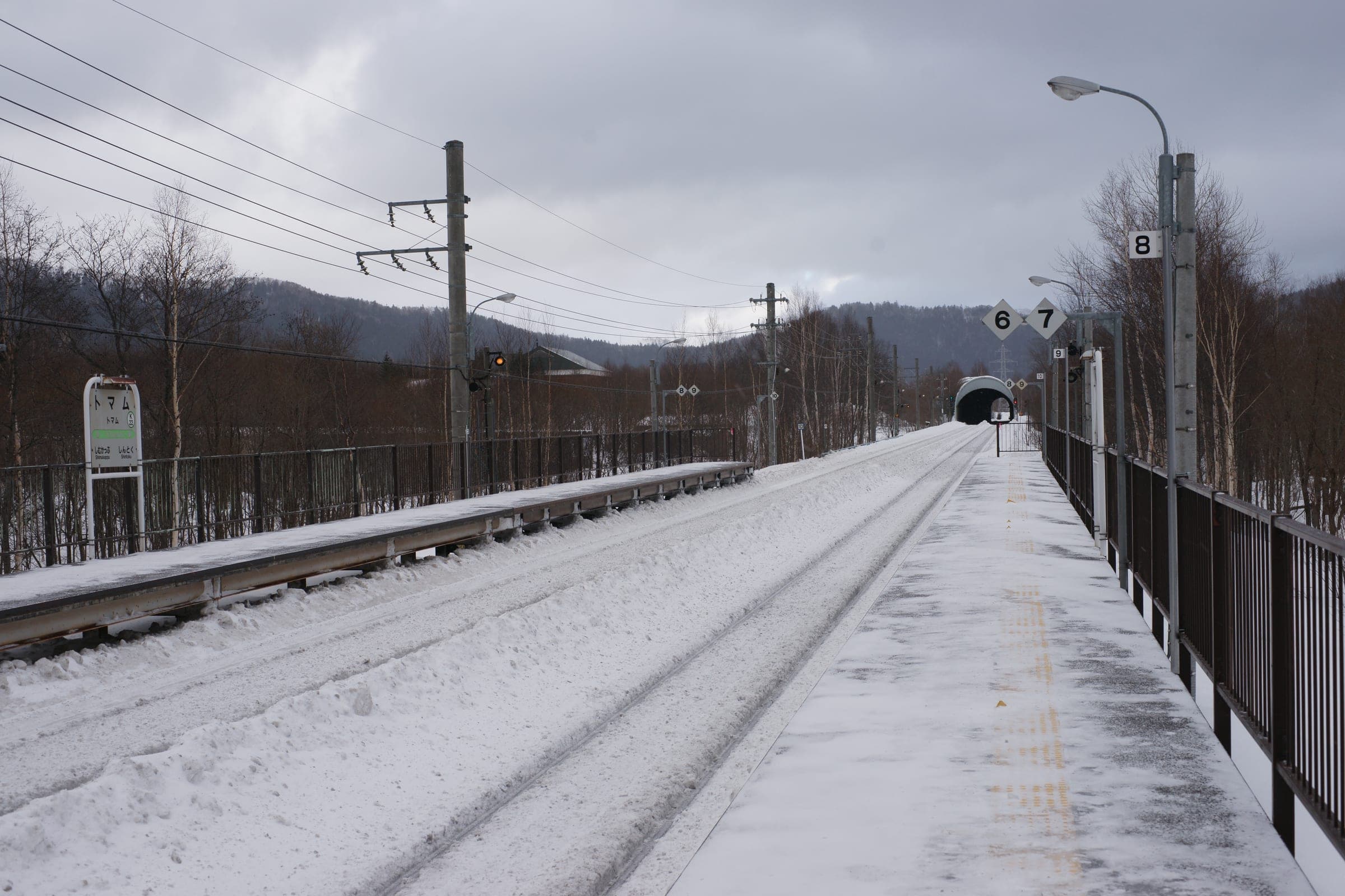 Snow lines the tracks at Tomamu Station on a winter day