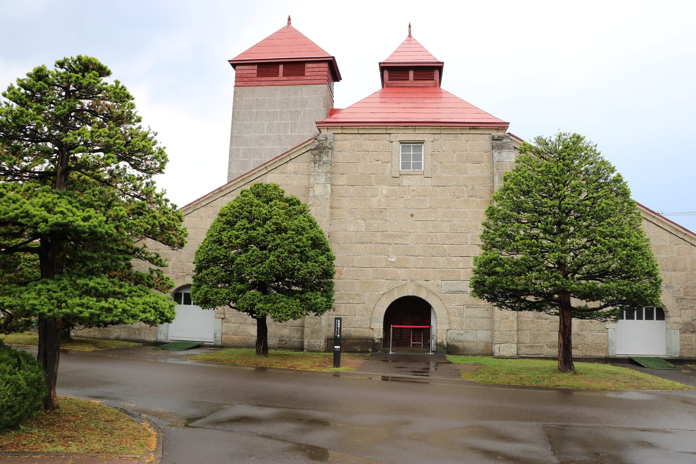Two kiln towers with red roofs stand between pines at the Yoichi distillery