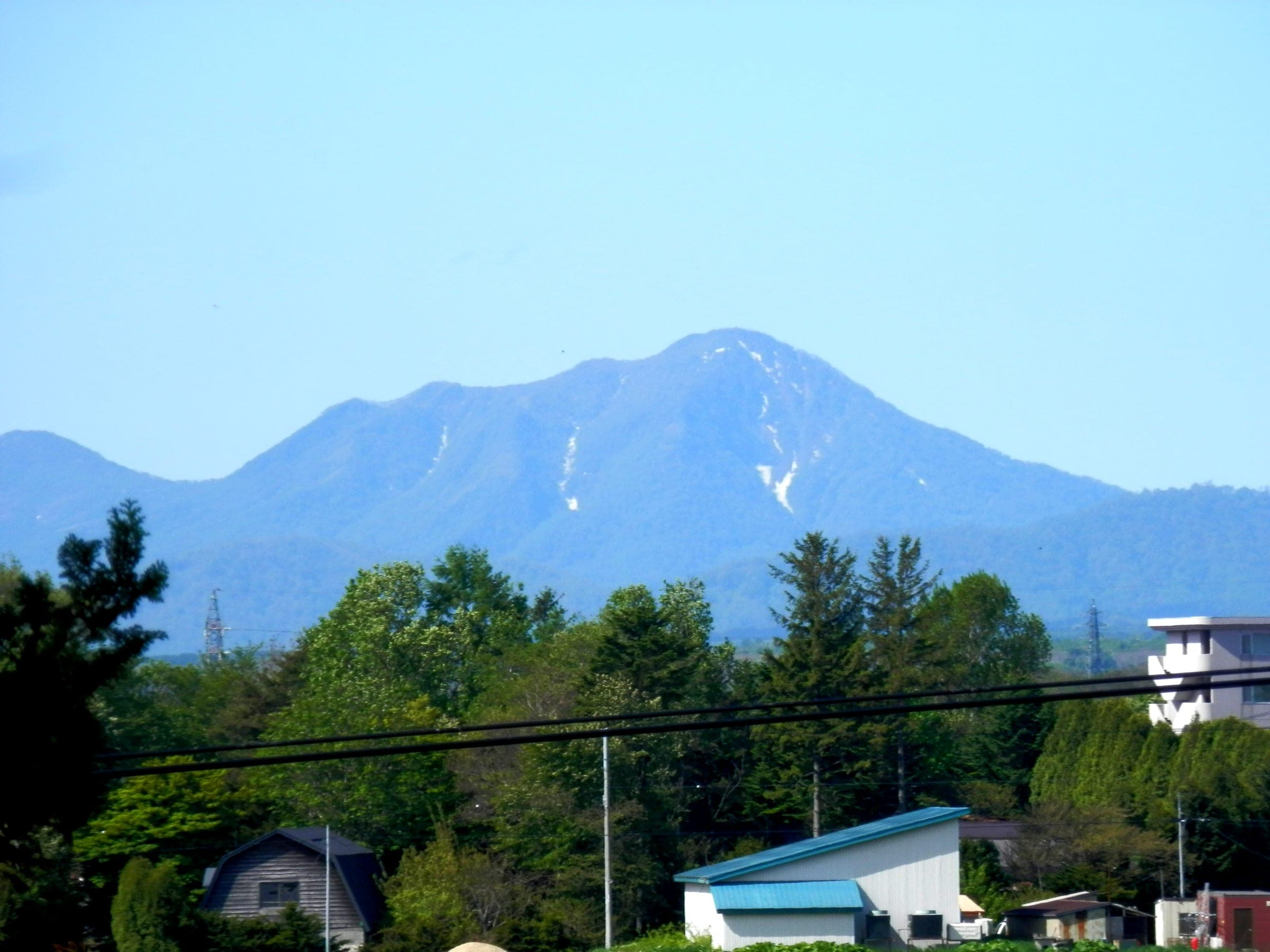 Fuppushi-dake carries streaks of late snow on the horizon, seen from Eniwa about 30 km away