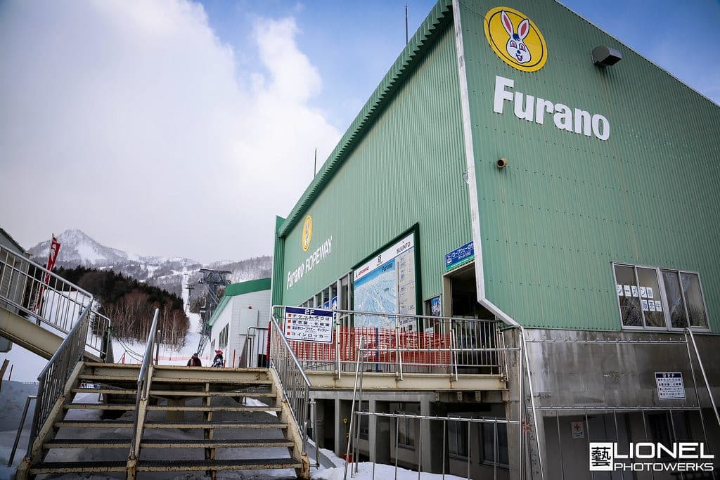 The green Furano Ropeway base station with the snowy ski slopes of Kitanomine behind