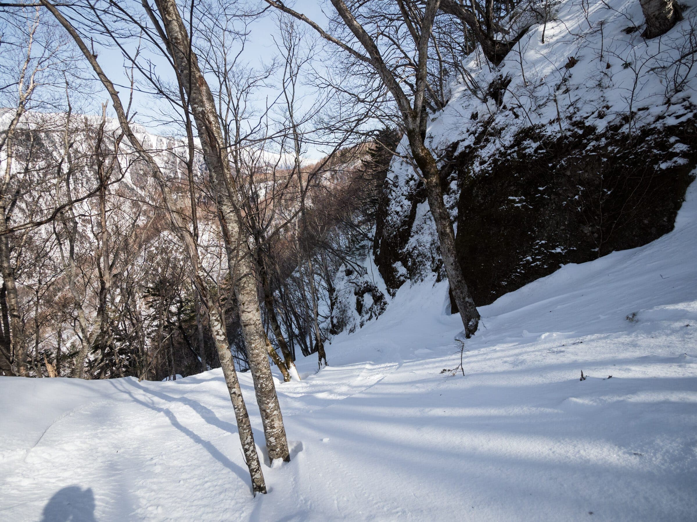 Snow and rock walls line the steep tree descent below the Kurodake ropeway toward Sounkyo