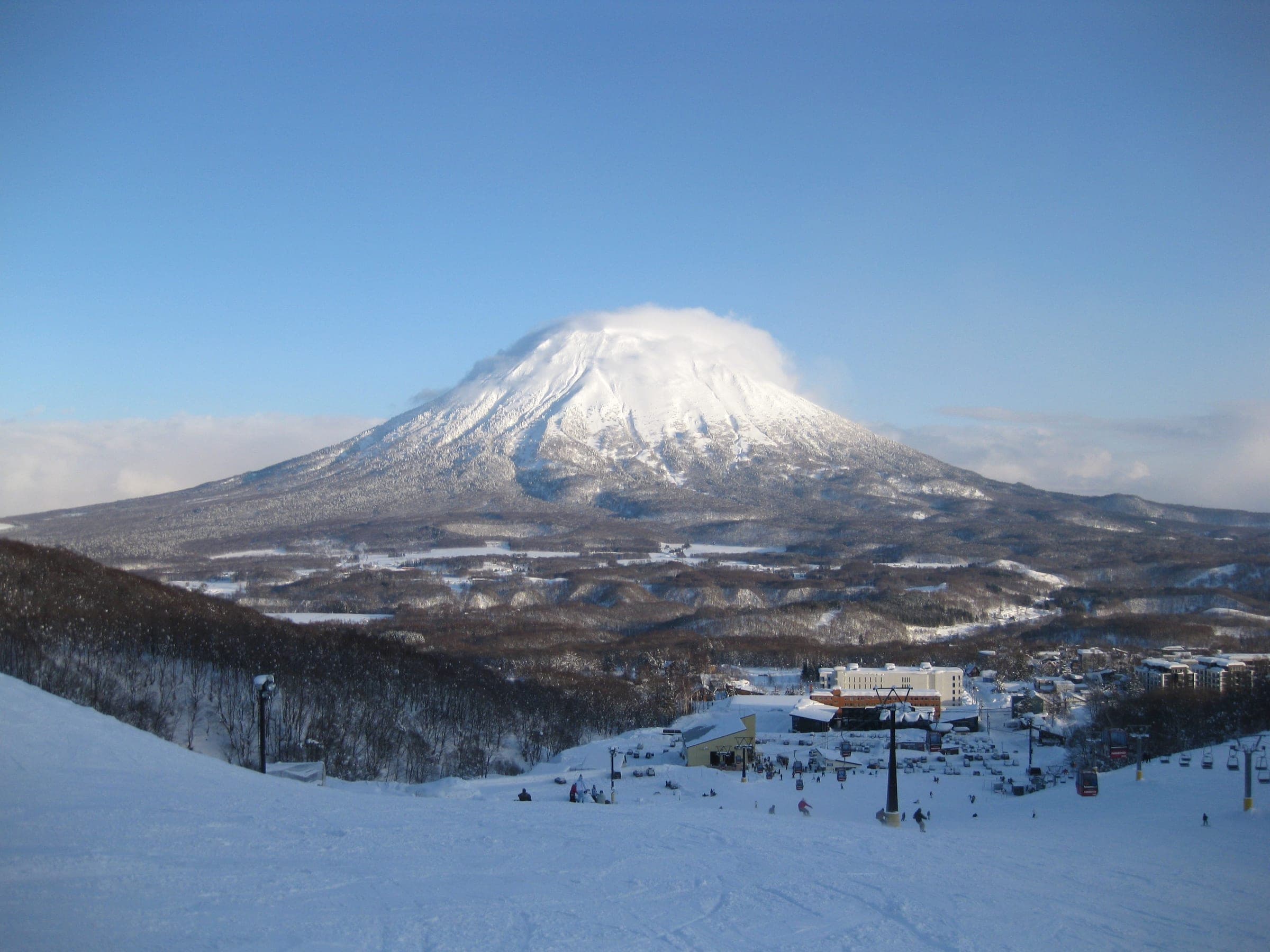Mt. Yotei stands over snowy forest and a ski lift on a clear winter day