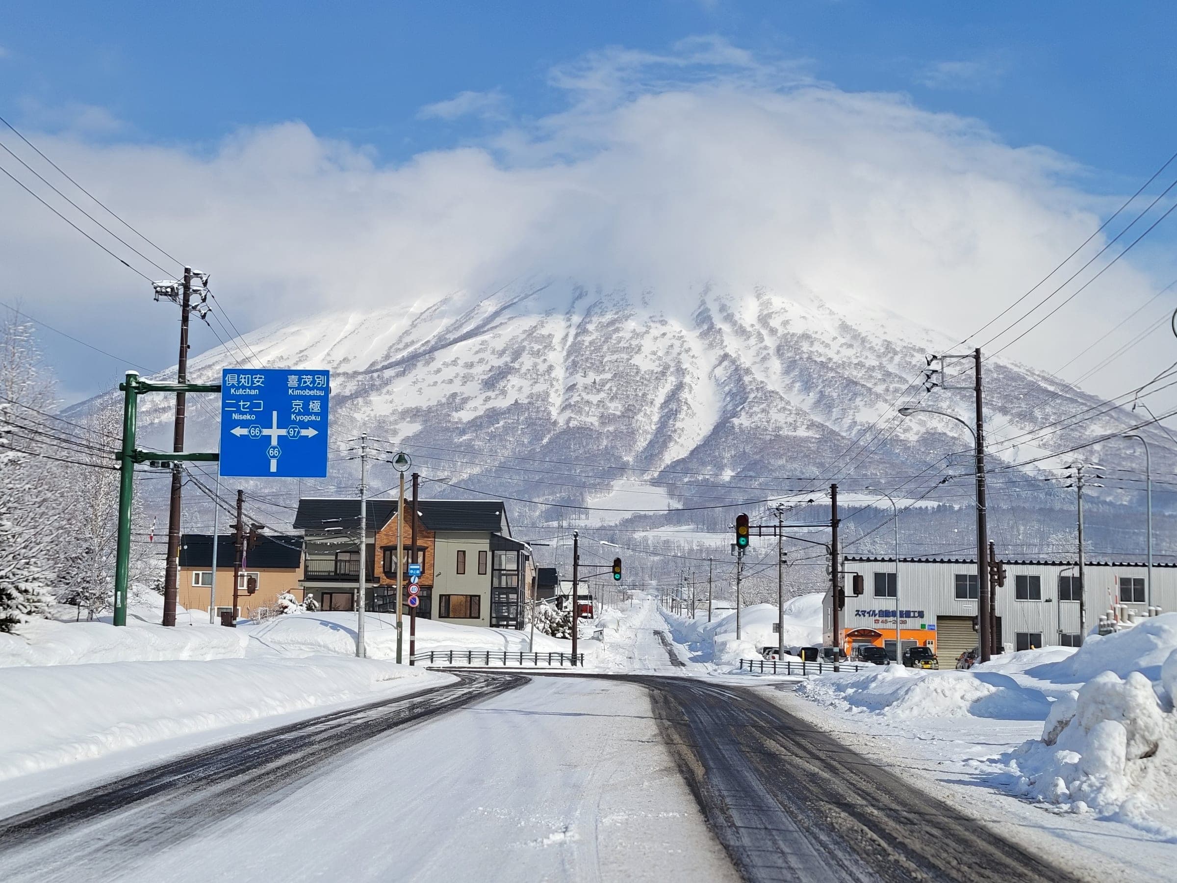 Cloud clears from snowy Mt. Yotei above a small town street in winter