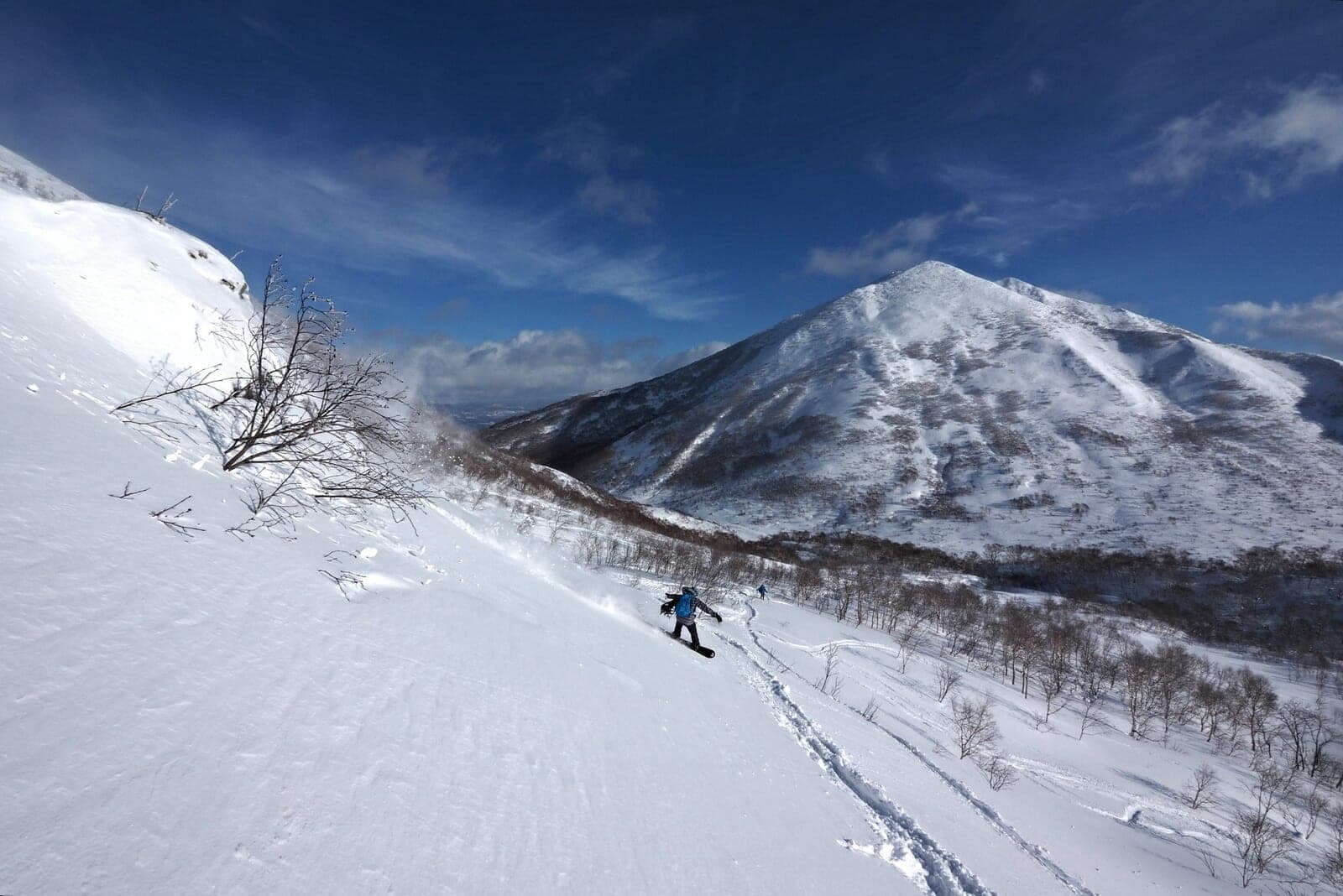 A skier rides down the south ridge of Iwaonupuri under a clear blue sky