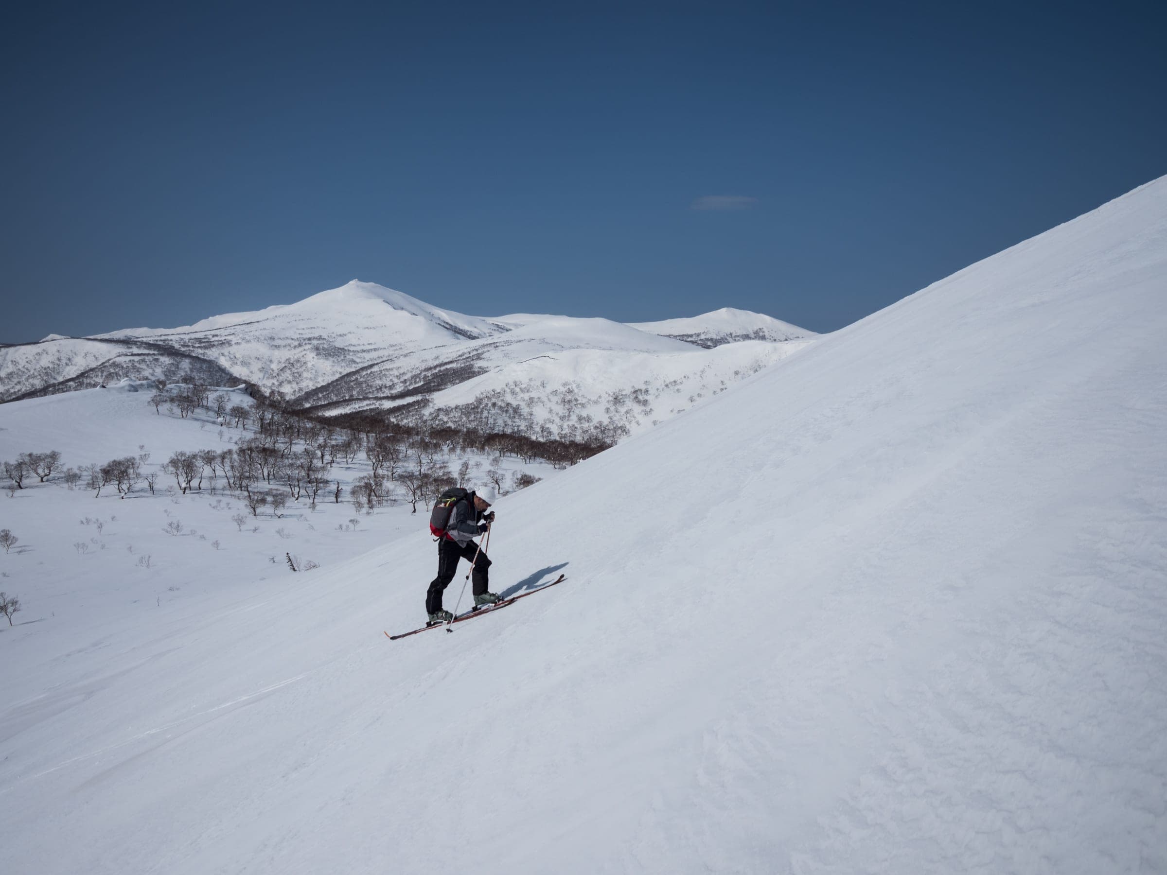 A skier descends the broad south face of Shakunage-dake with the Niseko Range behind
