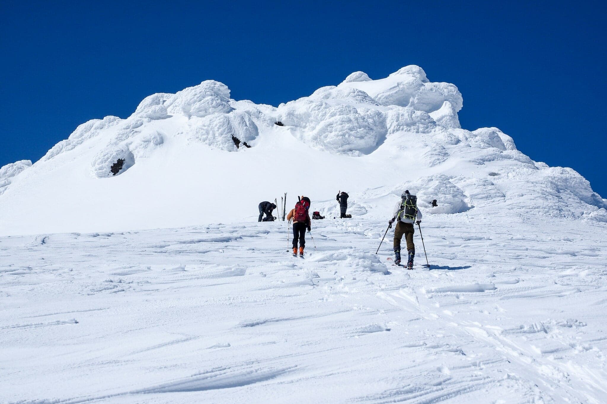 Ski tourers approach the rime-encrusted rock summit of Mekunnai-dake