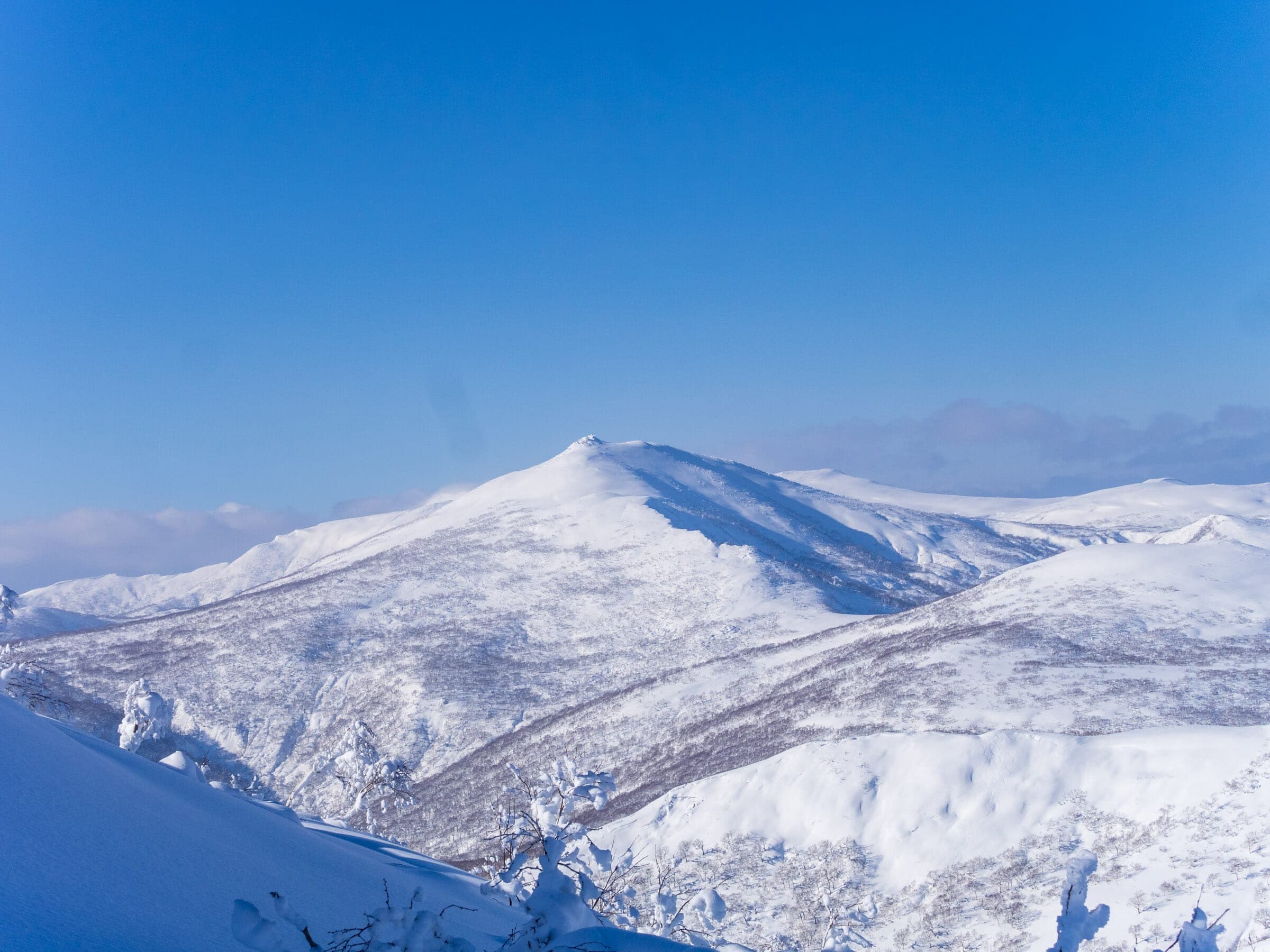 The snow-covered dome of Shakunage-dake stands above the Niseko Range on a clear day