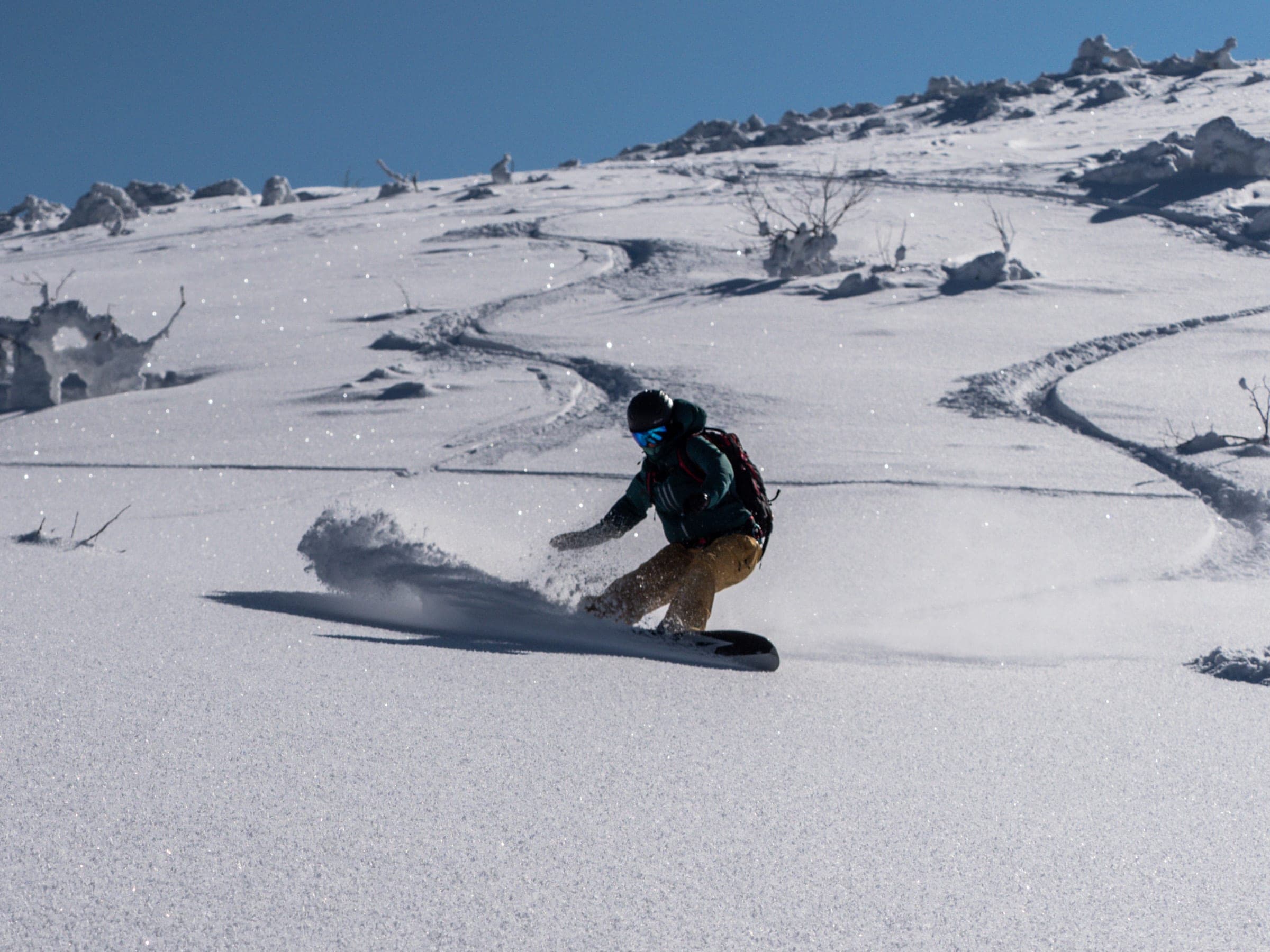 A snowboarder carves across rime-crusted snow on the west face of Nitonupuri