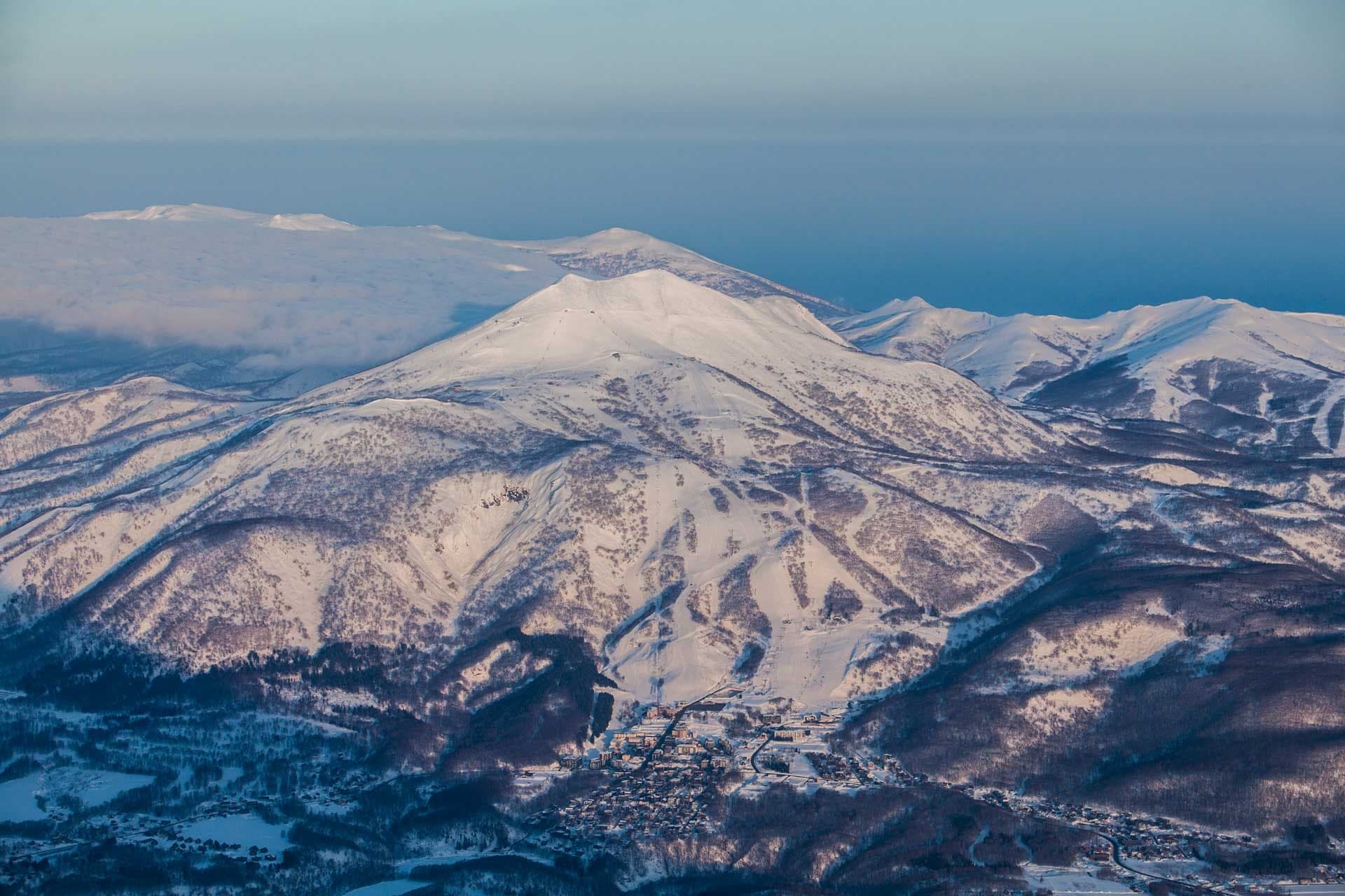 Low sun lights the snow-covered summit of Niseko Annupuri and the peaks of the Niseko range