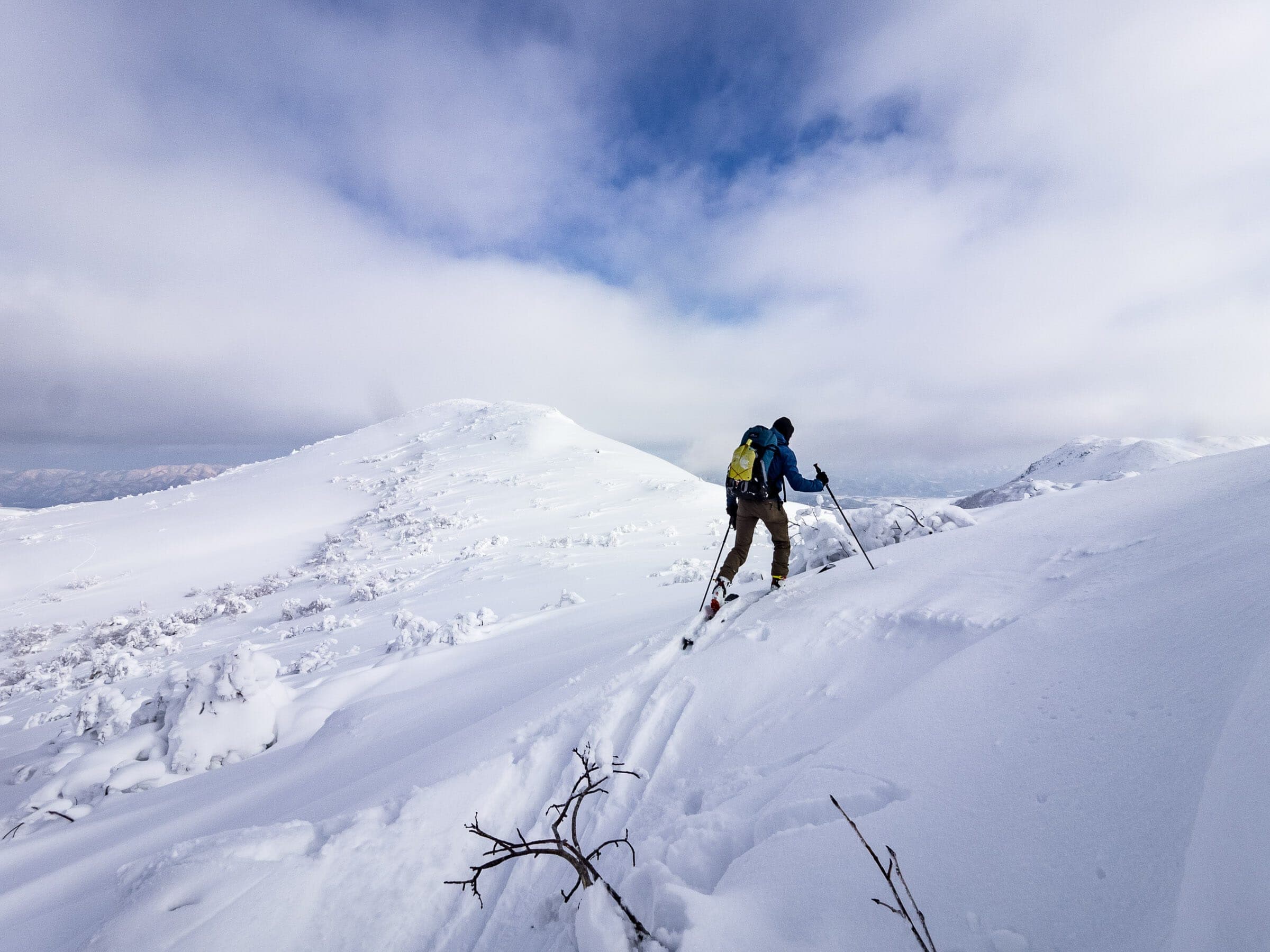 A ski tourer climbs toward the rounded summit of Nitonupuri in the Niseko Range