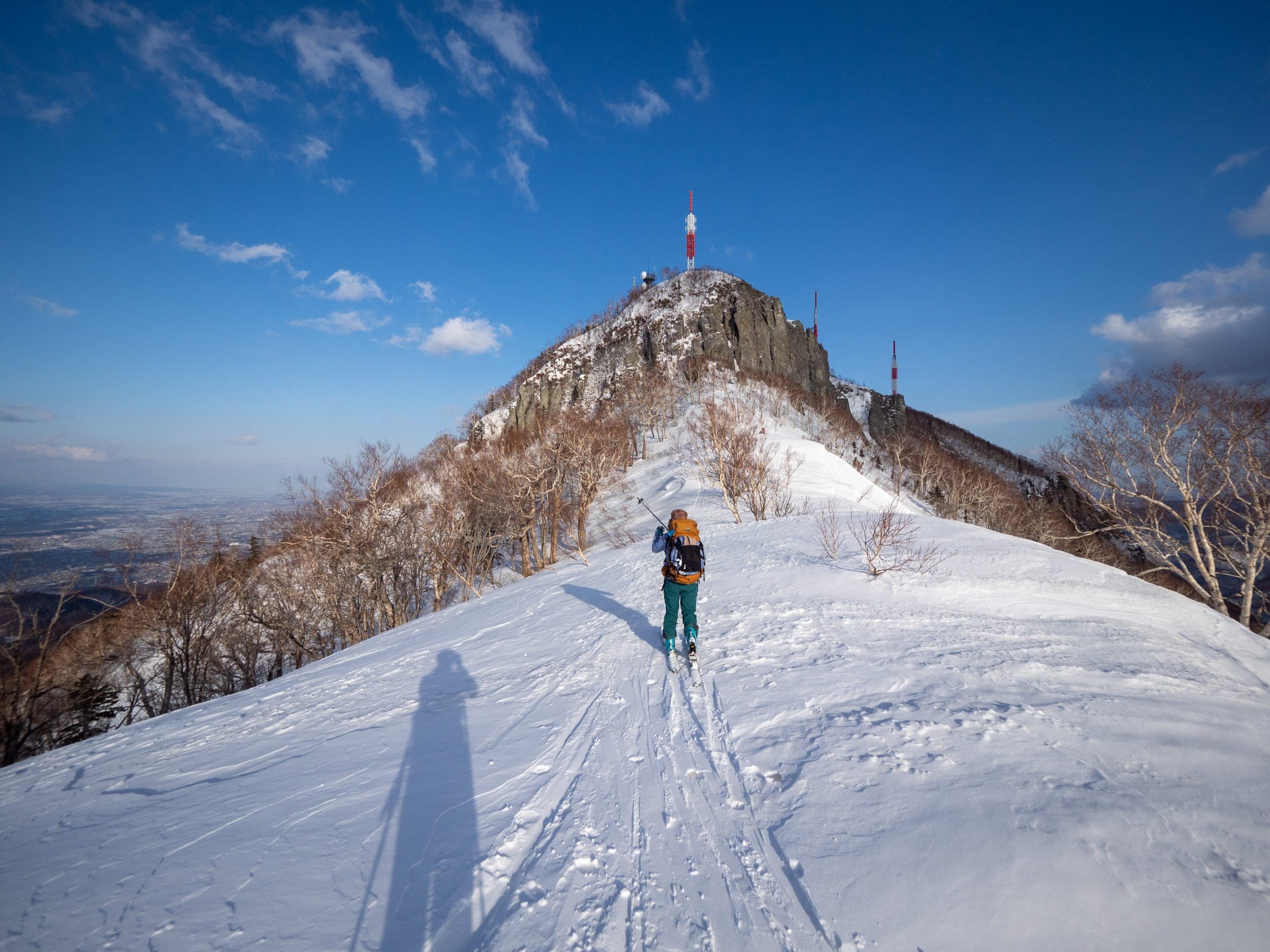 A ski tourer climbs the narrow ridge toward Teine-yama on the Kokusai to Teine traverse
