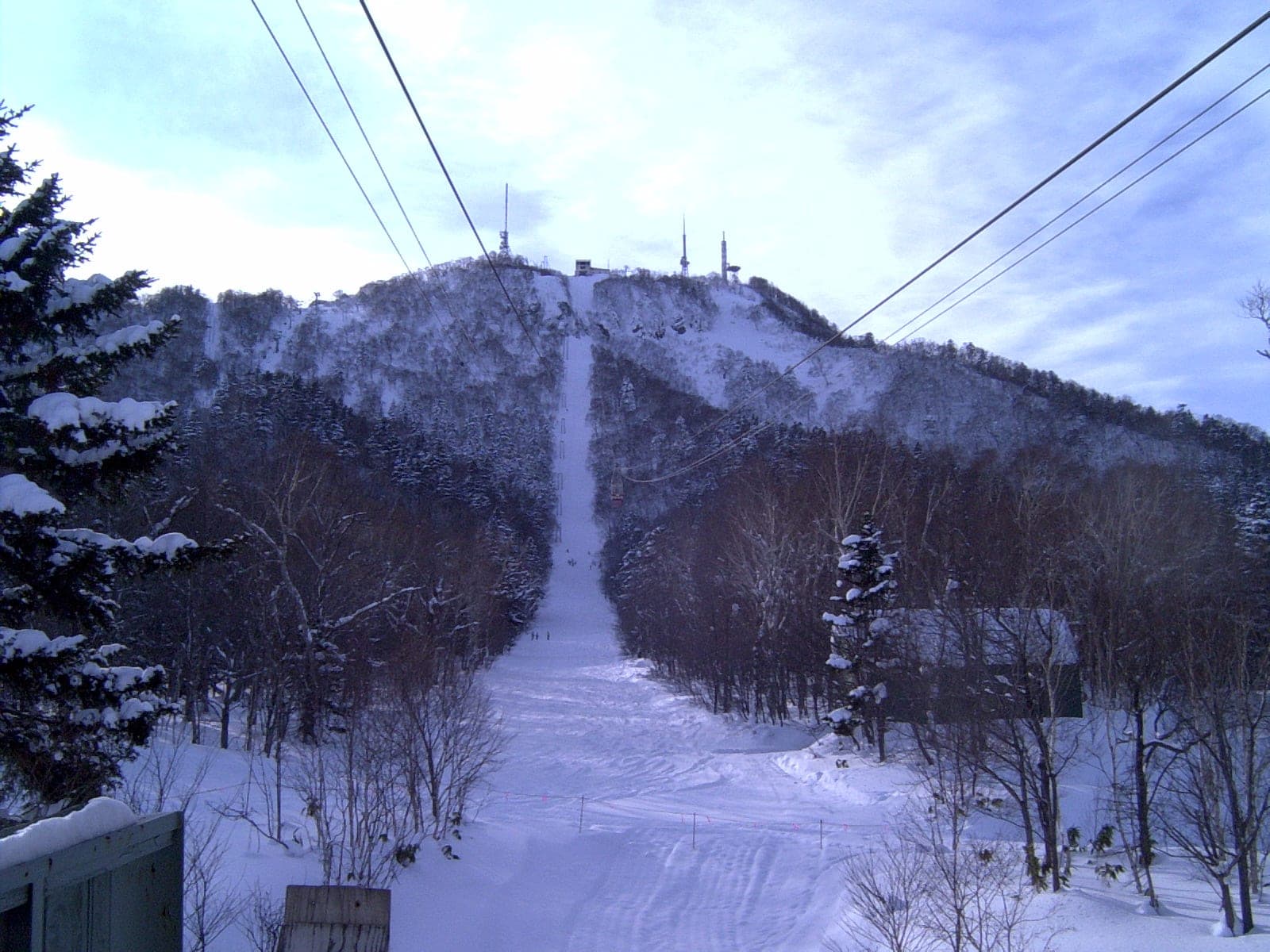 A cut ski run climbs to the snowy summit of Teine-yama and its antenna towers on the Okuteine traverse