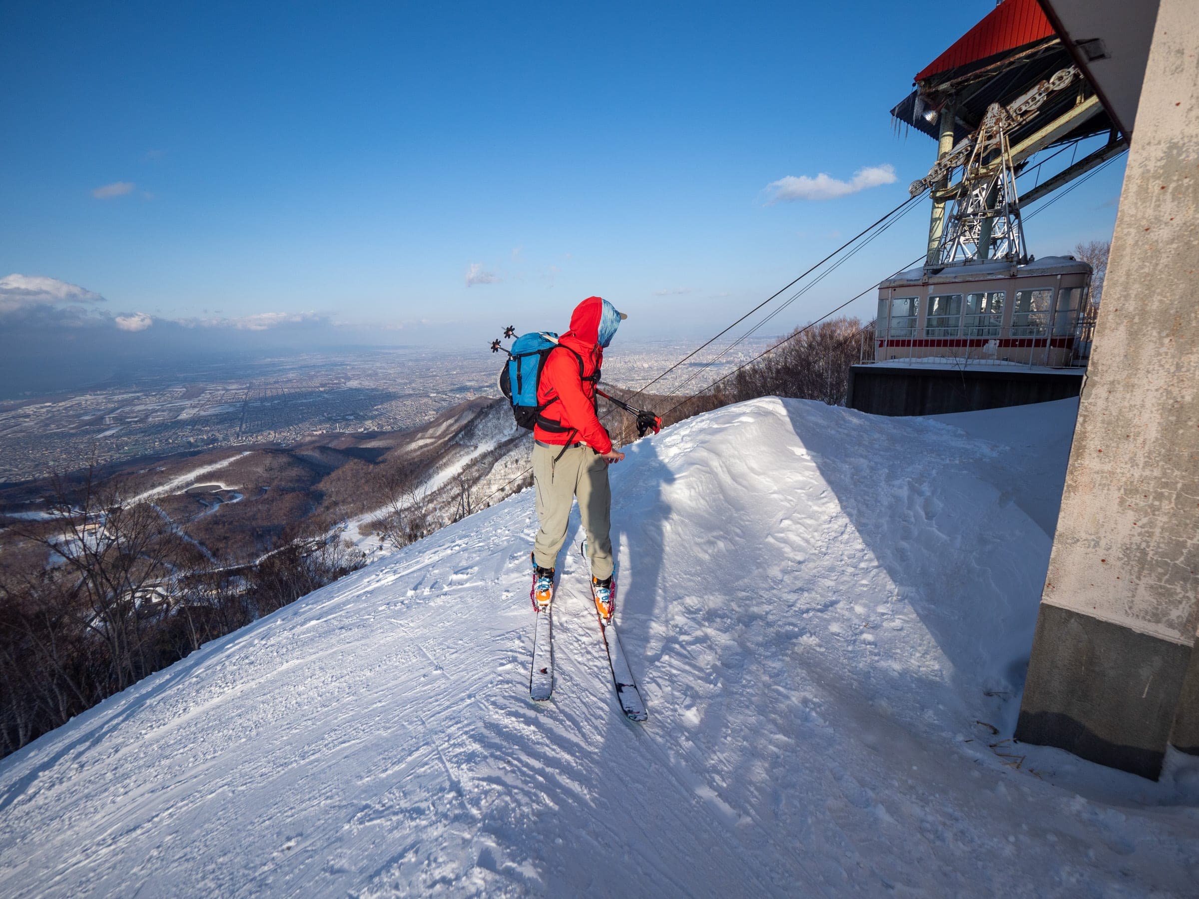 A ski tourer arrives beside the disused Teineyama Ropeway station at the top of Sapporo Teine