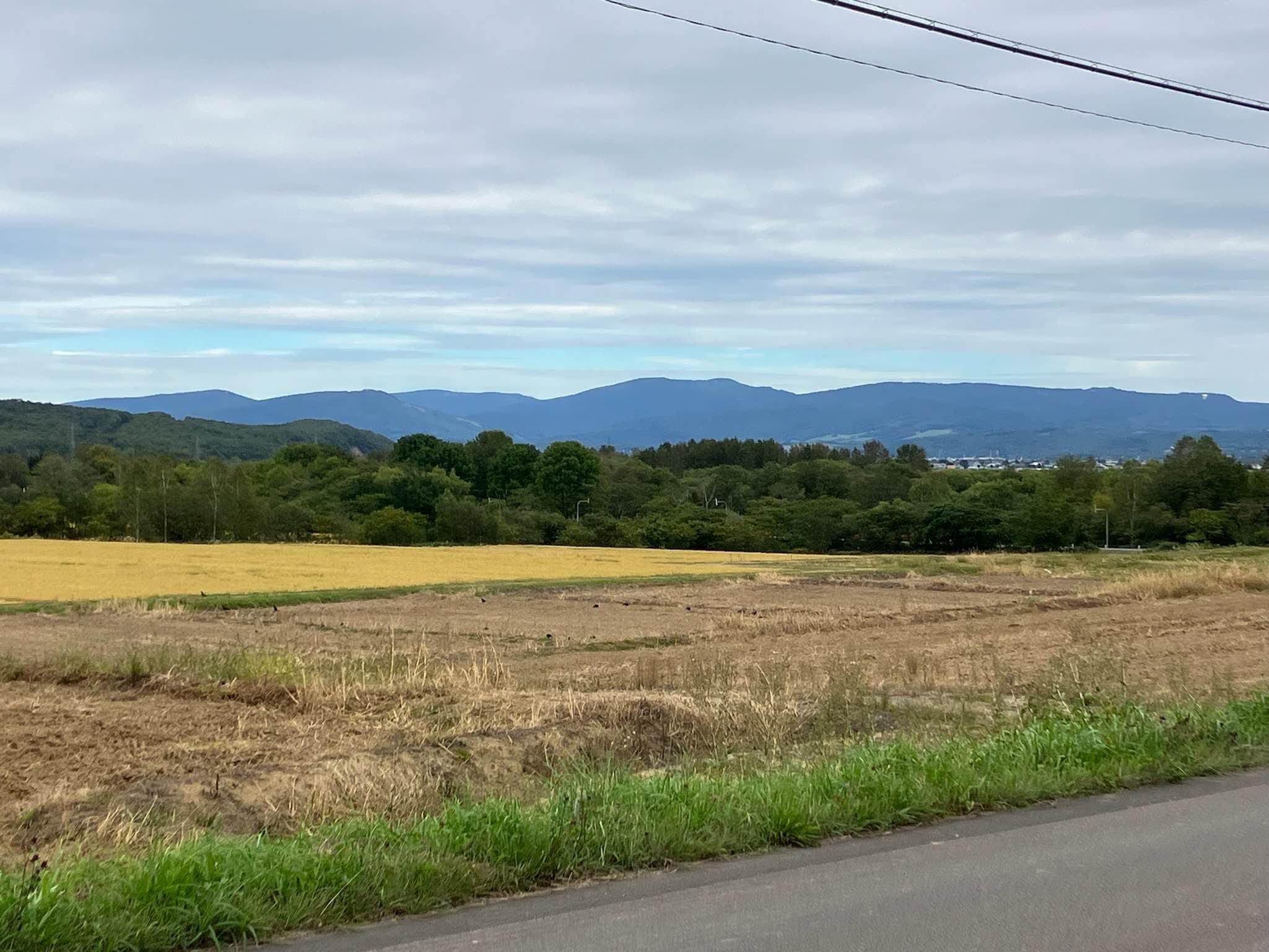 Mt. Piyashiri forms a long low ridge beyond autumn fields, seen from Nayoro city