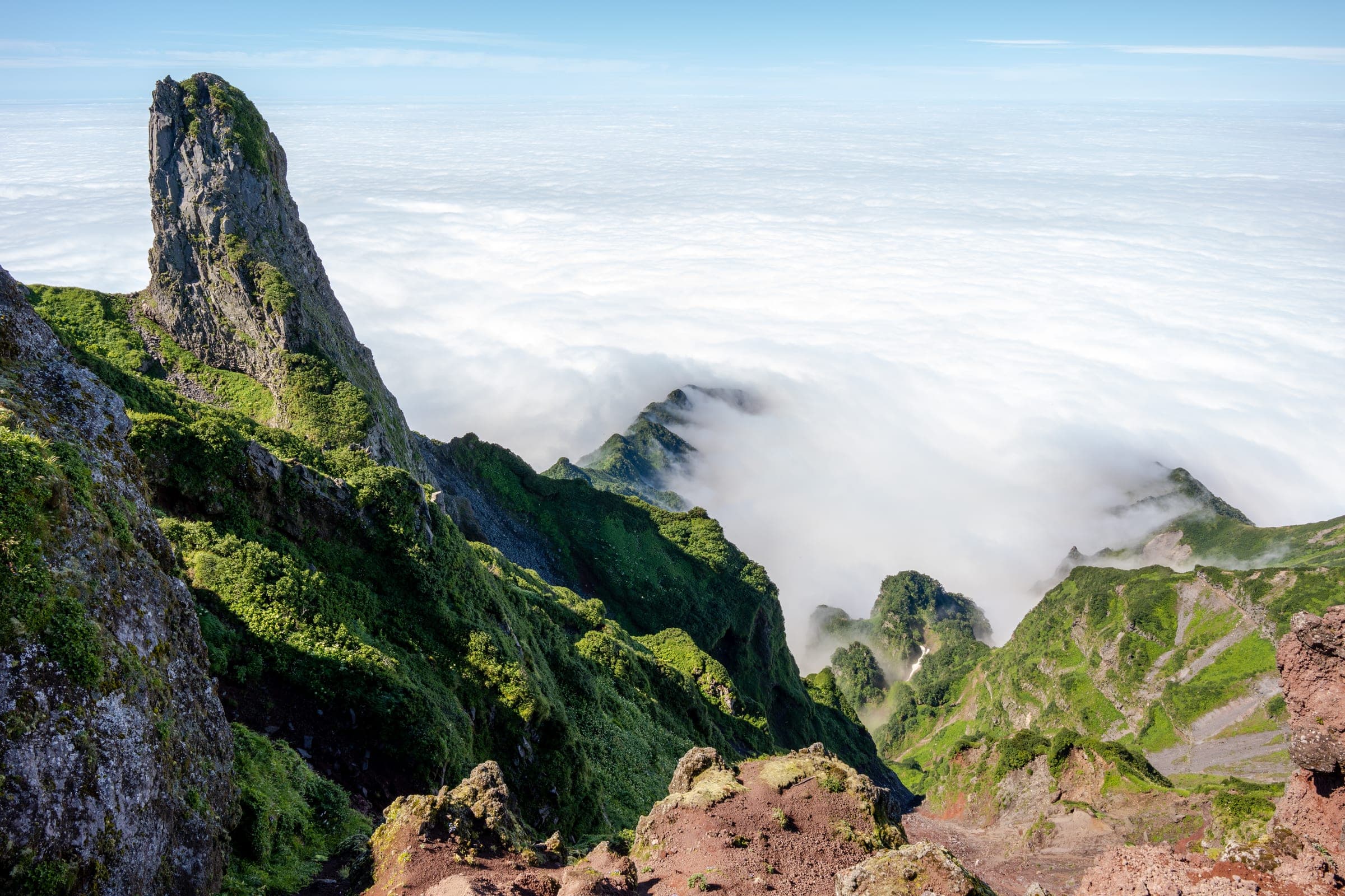 A rock spire rises above a sea of cloud on the upper slopes of Rishiri-zan