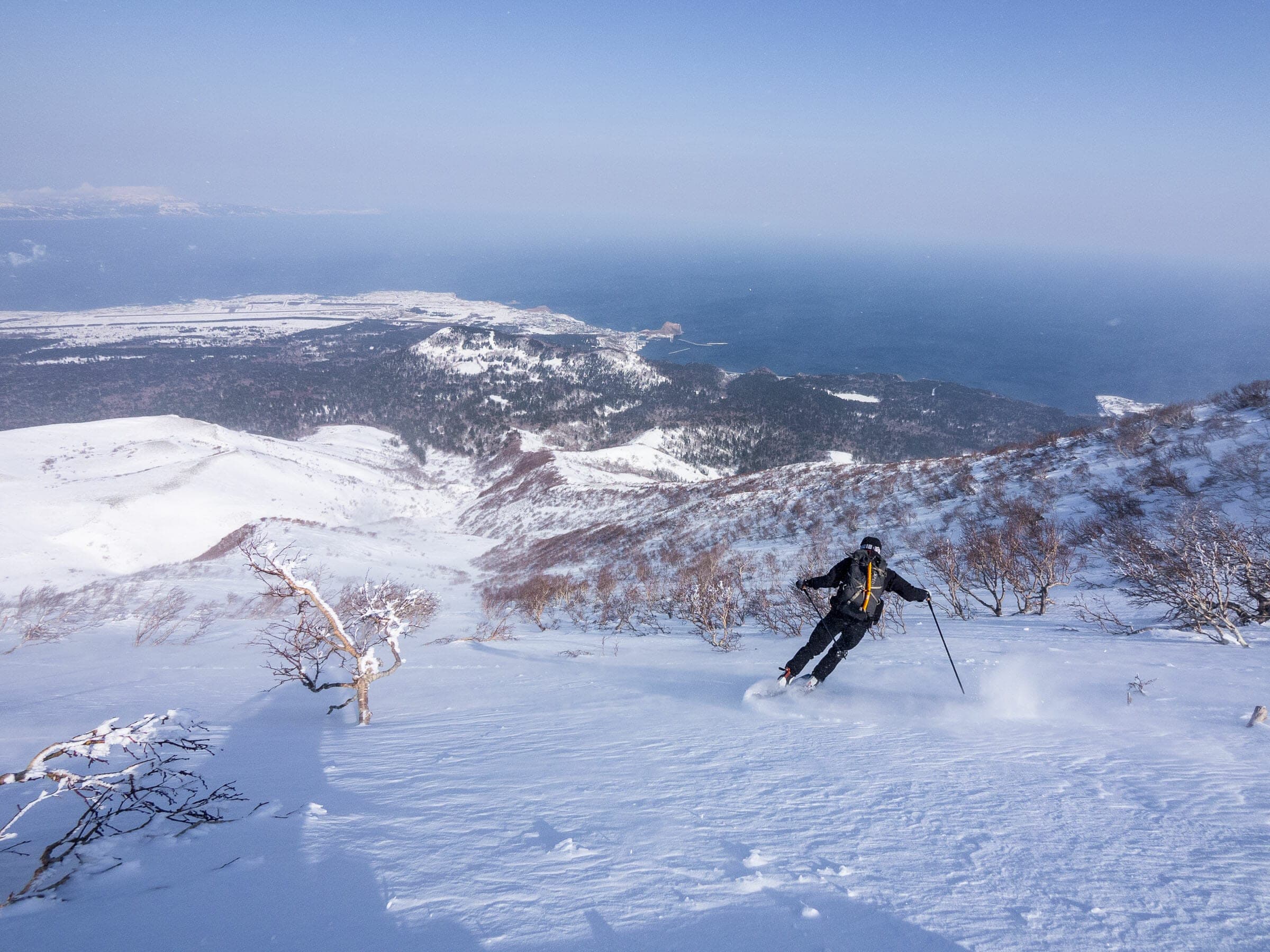 A skier descends the Oshidomari north ridge of Rishiri-zan above the sea