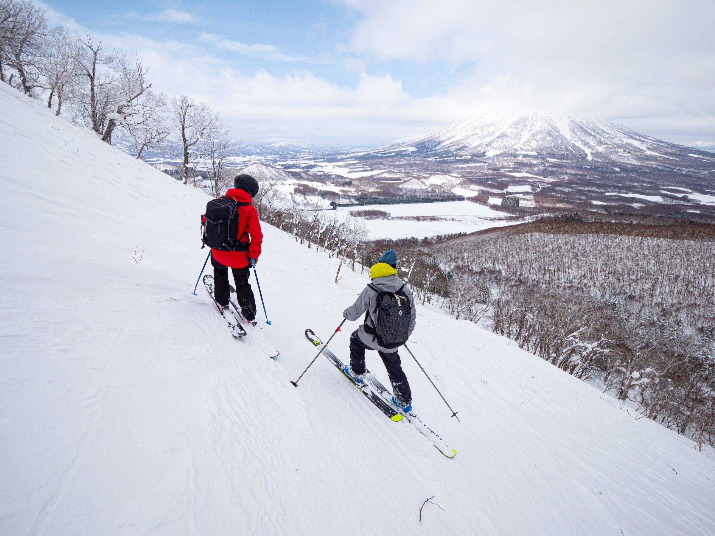 Two skiers descend the northwest side of Shiribetsu-dake above forest and farmland