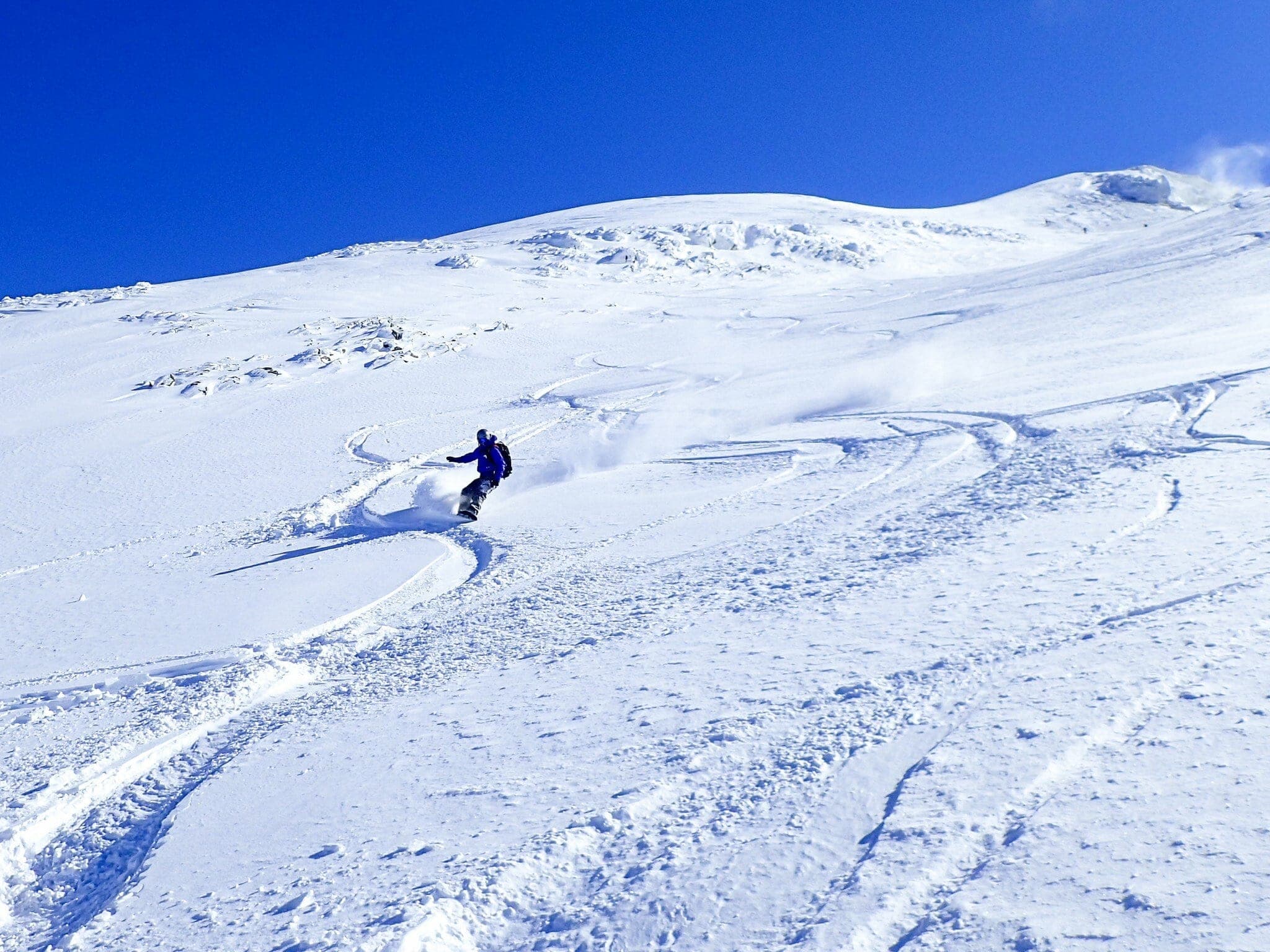 A skier carves across open snow on the Taisho Crater route up Maetokachi-dake