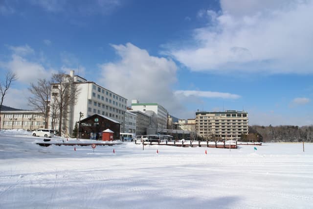 Lakeside hotels at Akanko Onsen stand behind the frozen, snow-covered surface of Lake Akan