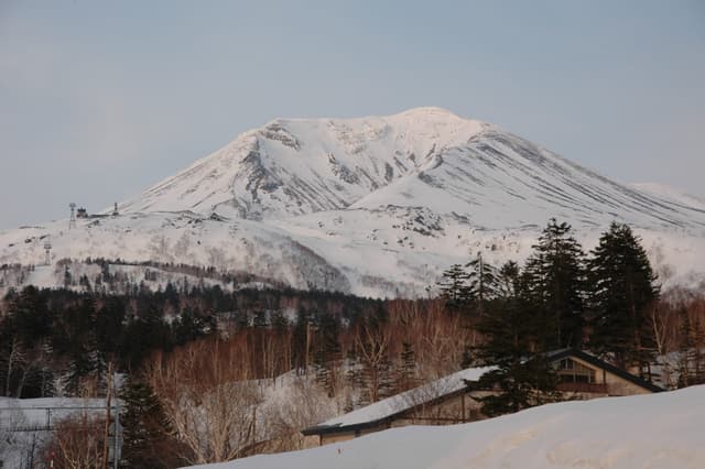 Snow-covered Mt. Asahidake rises behind the inns of Asahidake Onsen in winter
