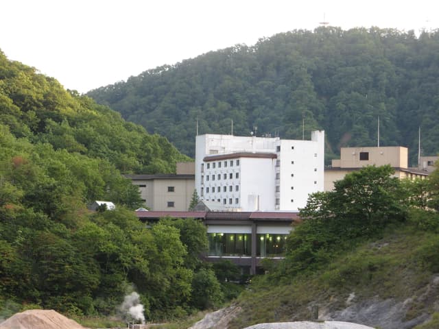 Dai-ichi Takimotokan rises from the green, wooded slopes of Noboribetsu Onsen in summer
