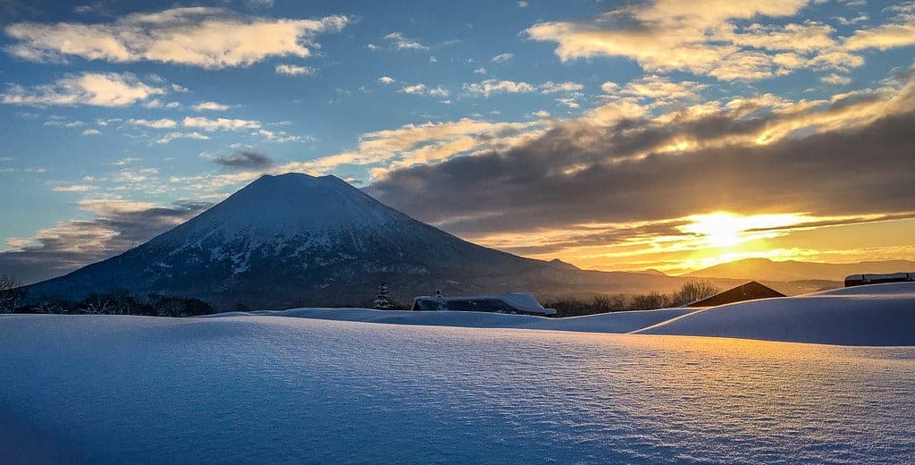 The sun rises beside Mt. Yotei over a snowfield in the Niseko backcountry