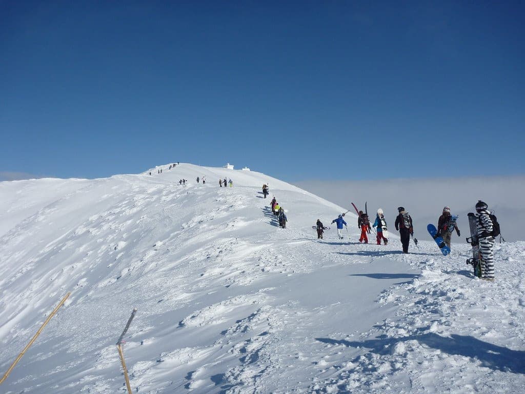 Riders bootpack along a snowy ridge toward the summit of Niseko Annupuri